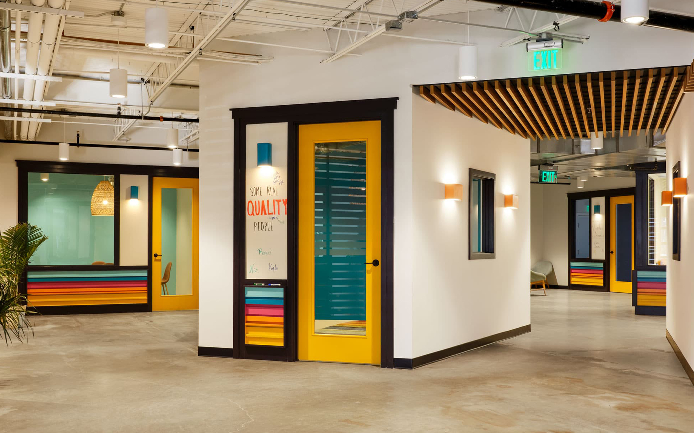 Siete HQ corridor with yellow doors and 'Quality People' wall mural under wood ceiling