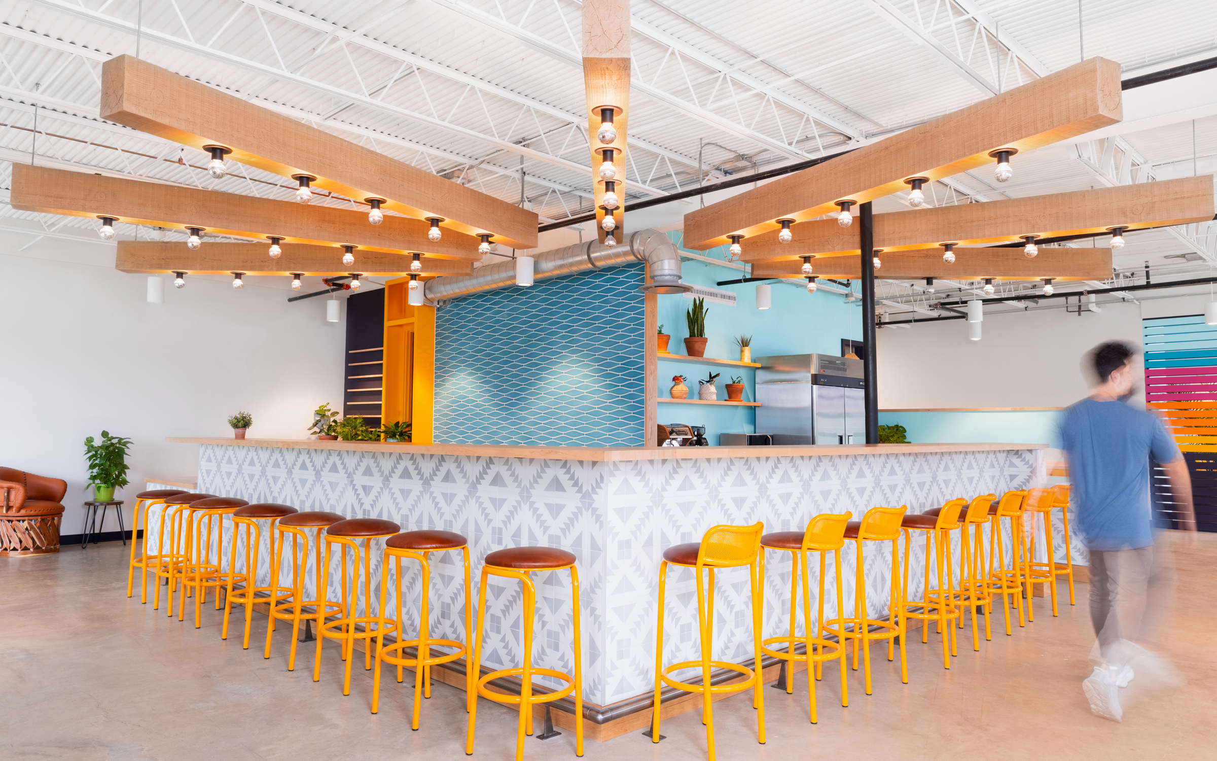 Siete HQ cafe bar with patterned tile counter and rows of yellow stools under wood beams