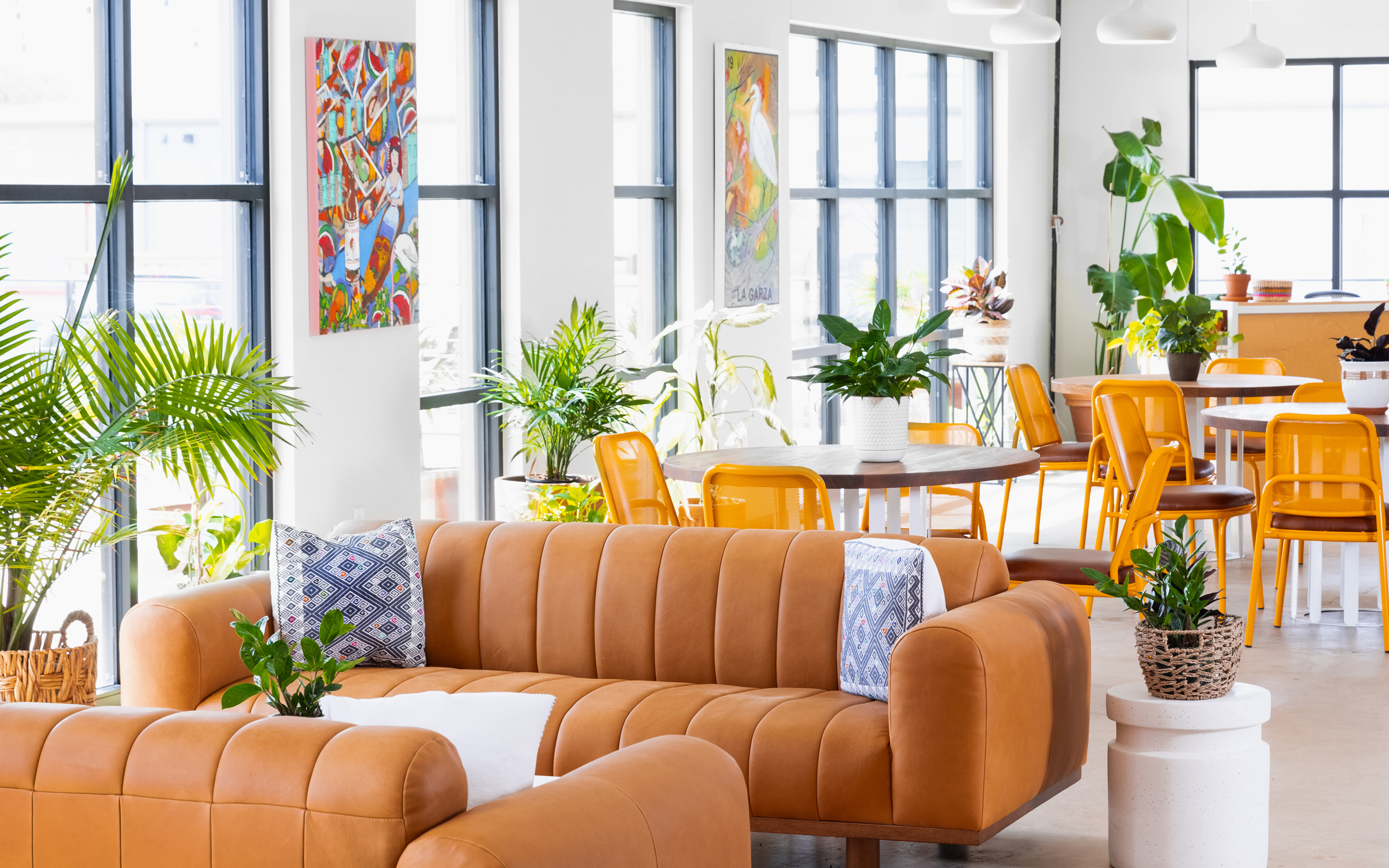 Siete headquarters lounge with caramel leather sofas, potted plants and colorful art on white walls