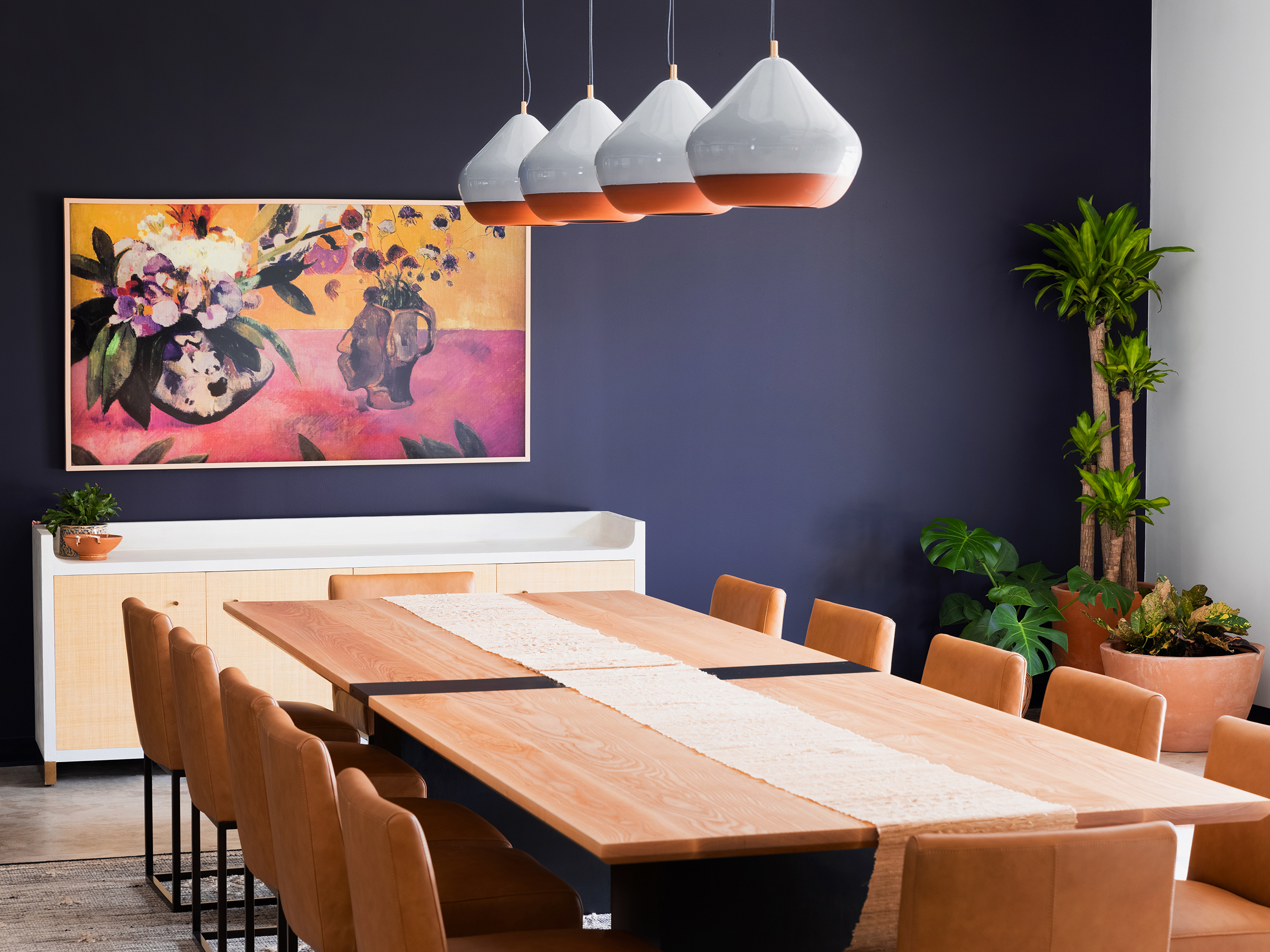 Siete HQ dining room with long wood table, leather chairs and floral painting