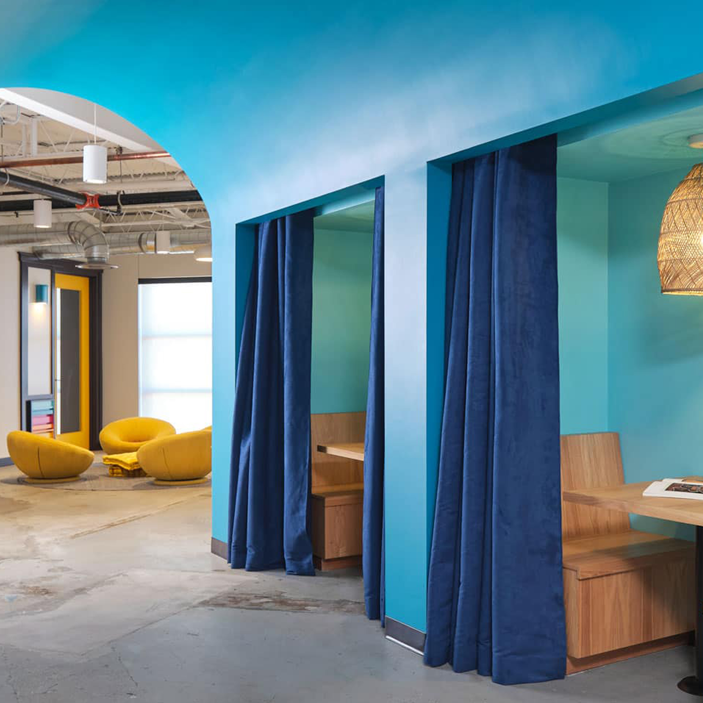 Siete HQ blue curtained meeting nooks with wood benches and yellow lounge chairs