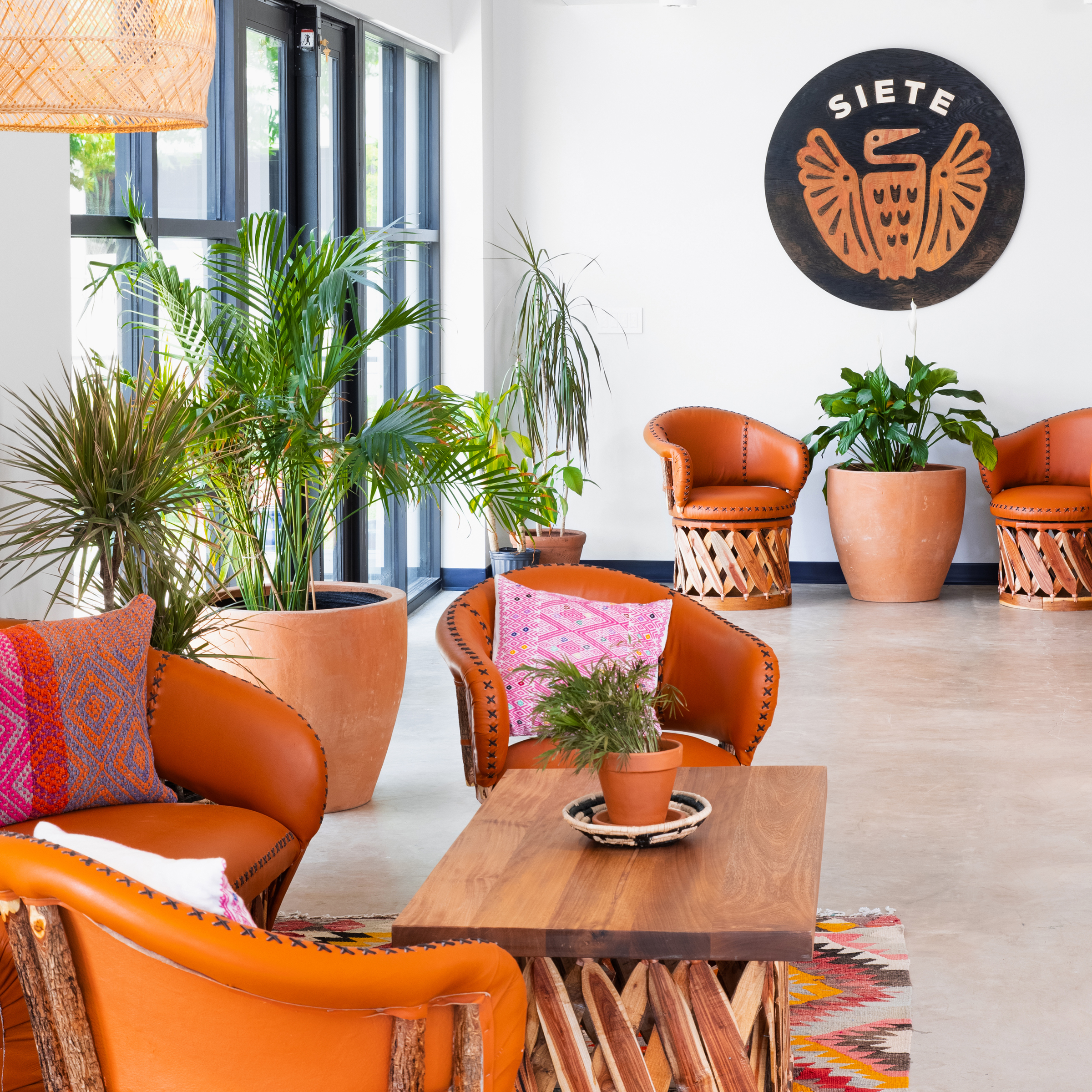 Siete headquarters lobby with leather chairs, terracotta planters and the black Siete eagle logo on the wall