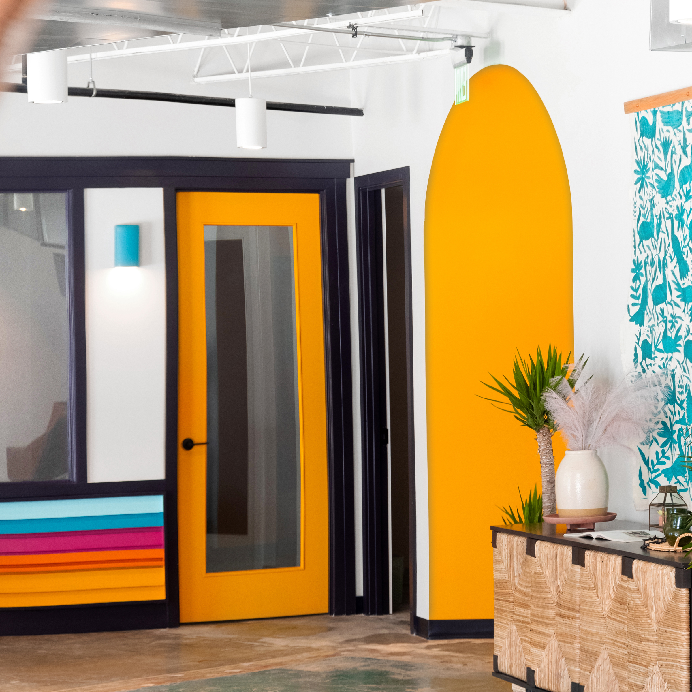 Siete HQ lobby with orange phone-booth door, painted arch and turquoise Otomi-print curtain
