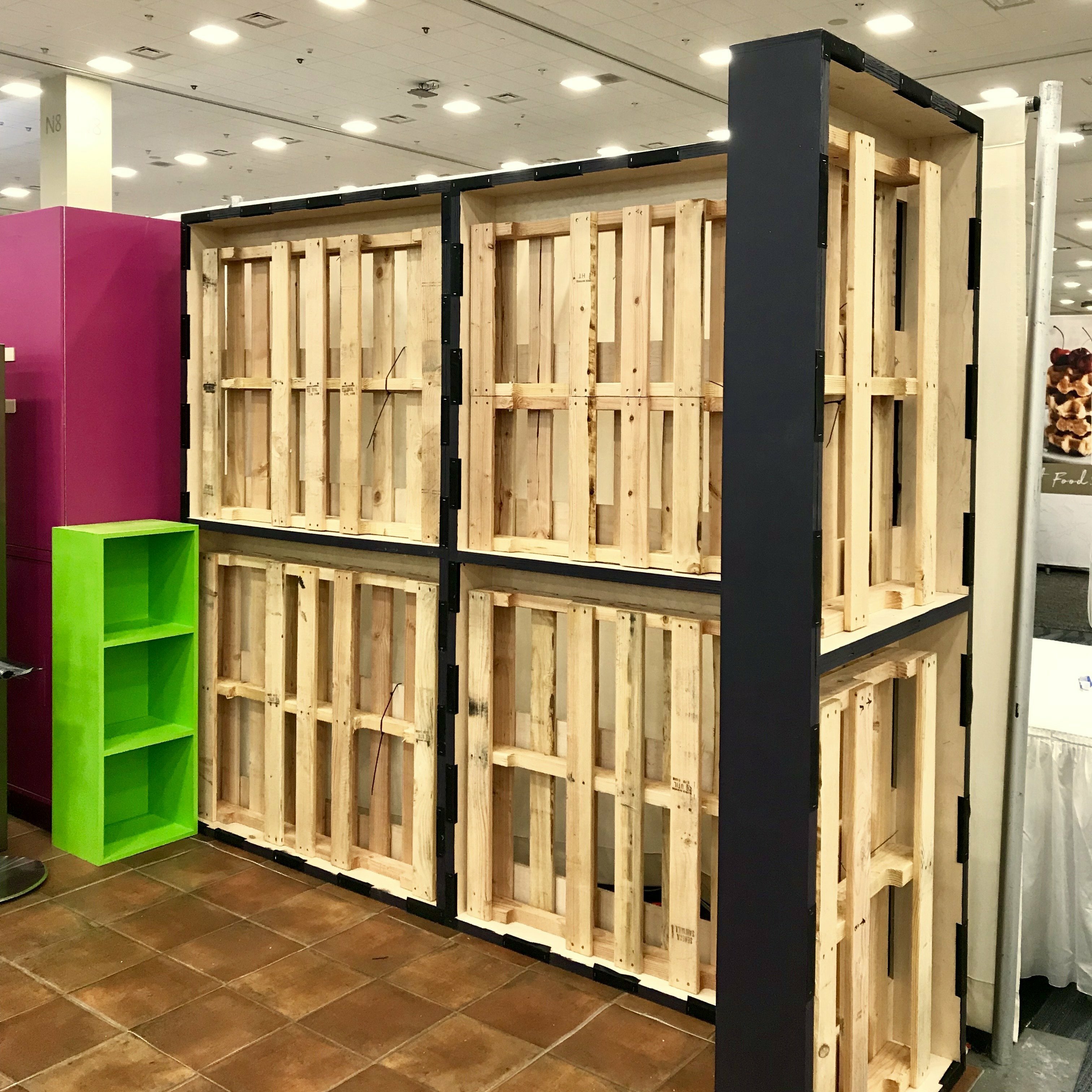 Wood pallet shelving wall and green cubby unit during Siete booth setup