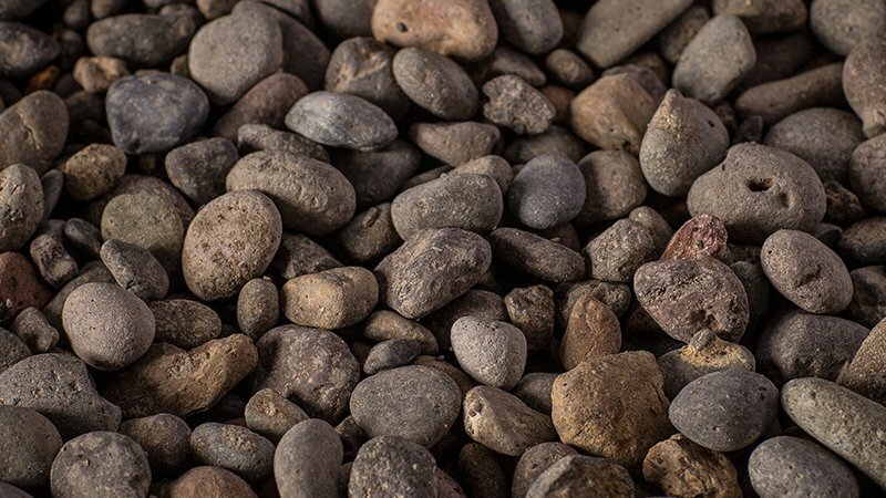 Close-up of smooth rounded river rocks in earthy brown and gray tones