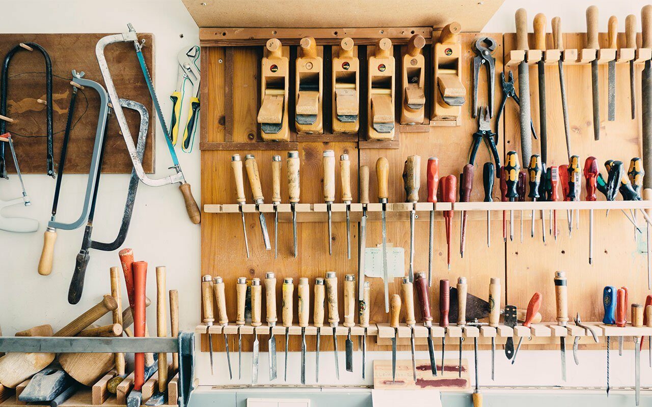 Woodworking wall neatly hung with hand saws, chisels, planes and files in a workshop