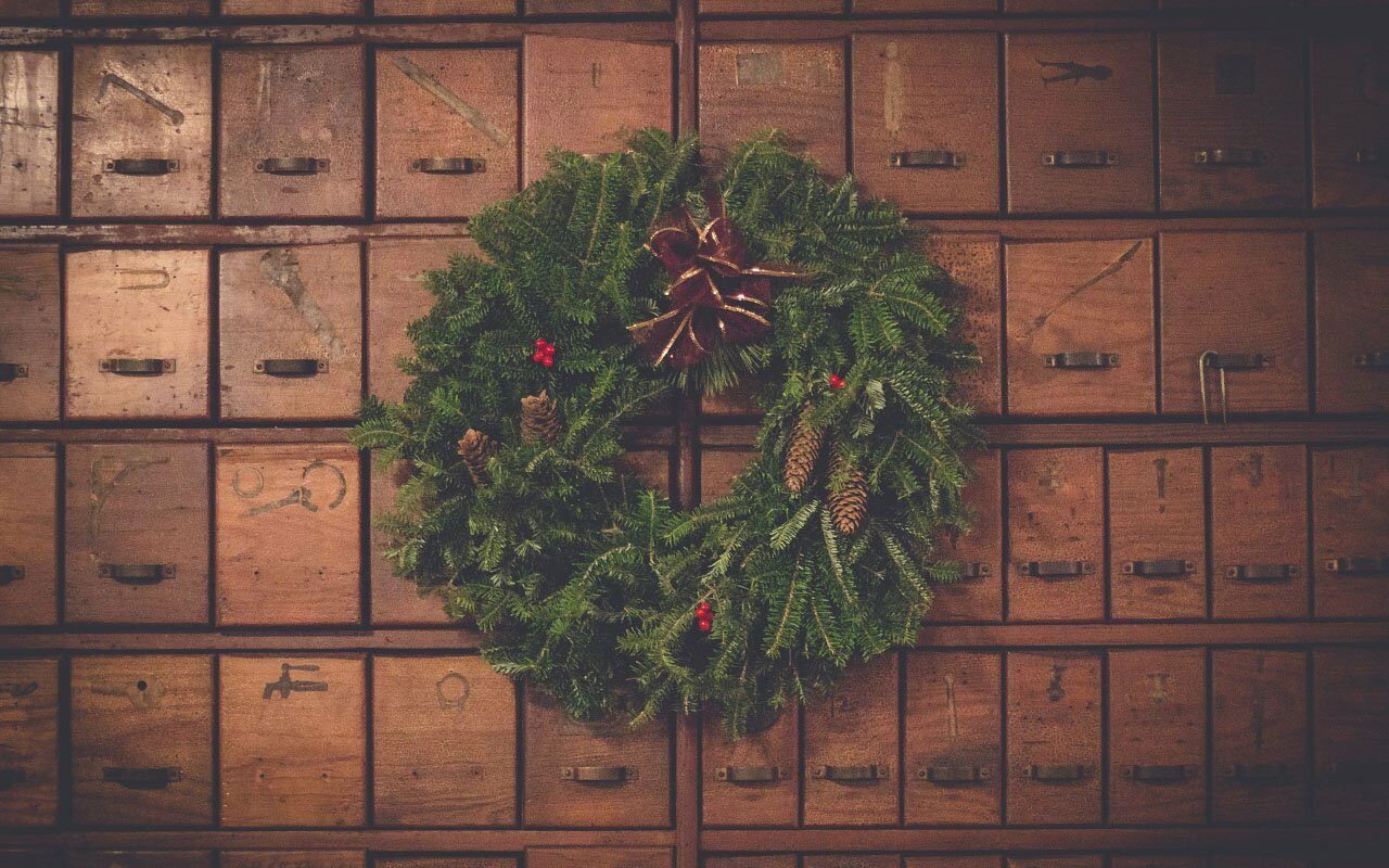 Evergreen holiday wreath with pinecones hanging on a wall of vintage wooden drawers