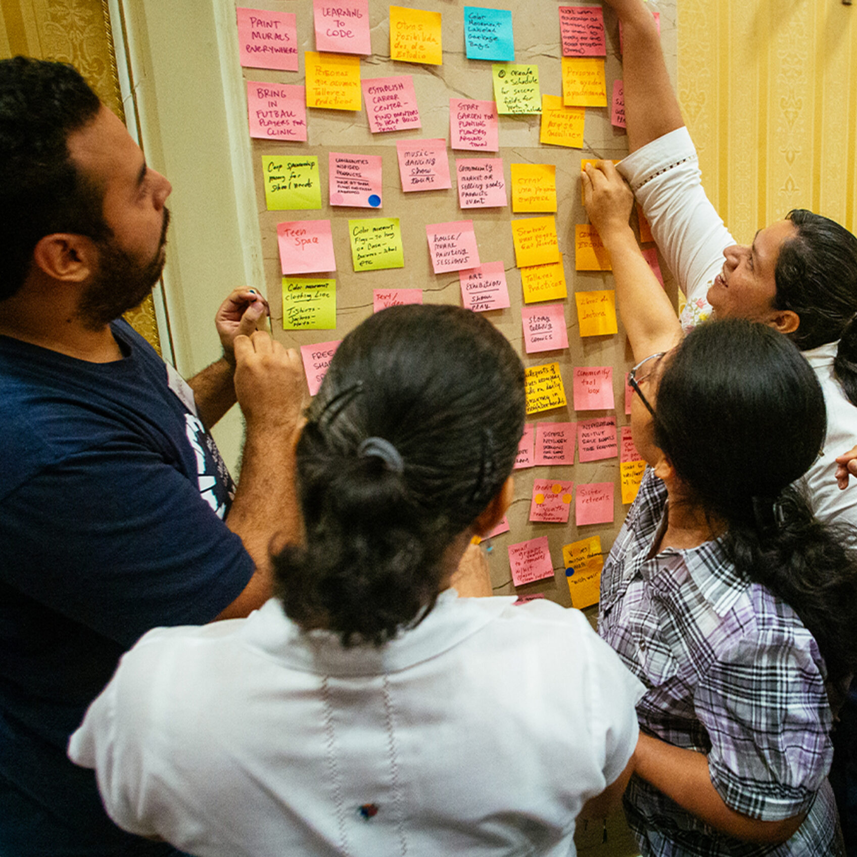 People clustering colorful sticky notes on a wall during a collaborative planning session