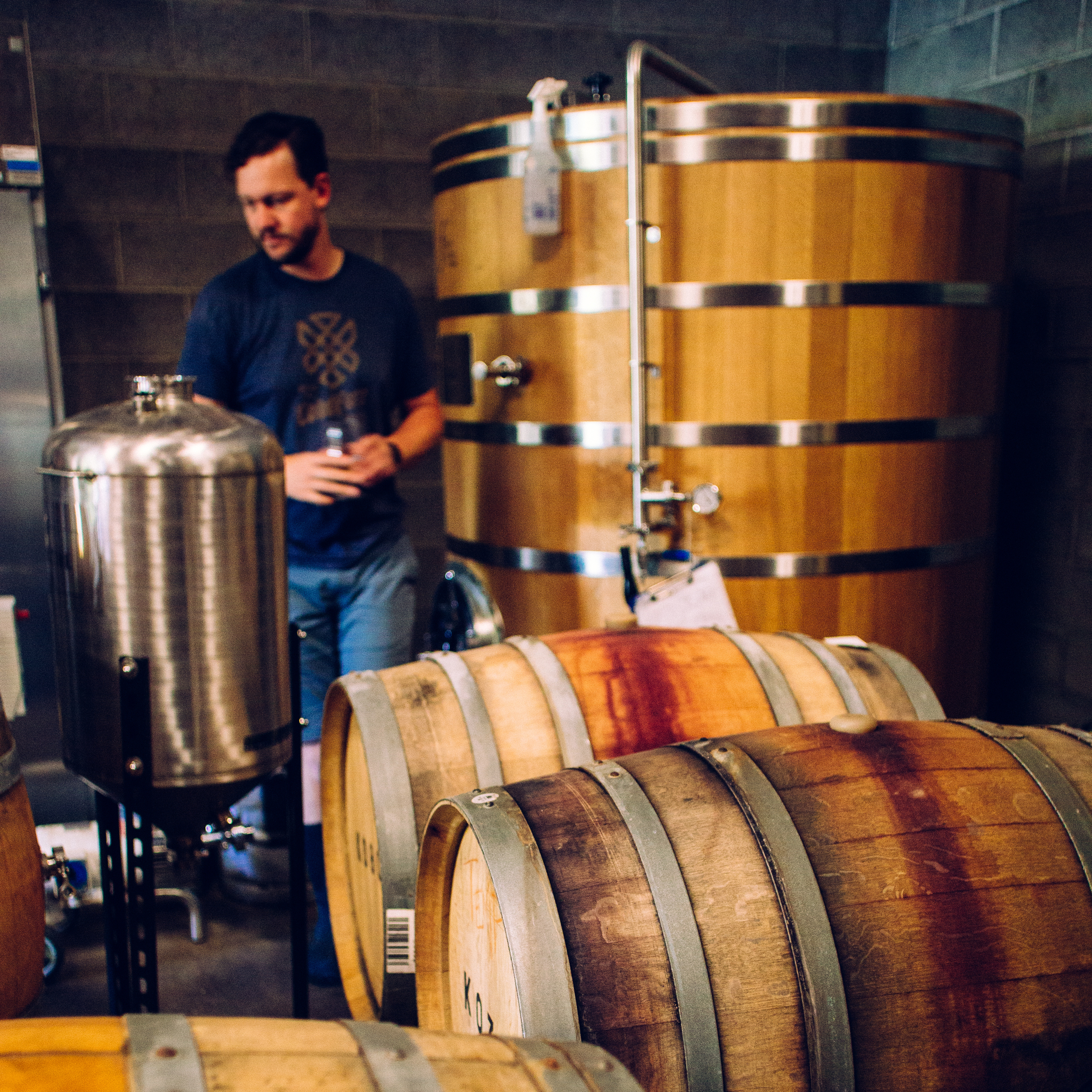 Brewer beside wooden foeders and stainless tanks among oak barrels at Coldfire brewery