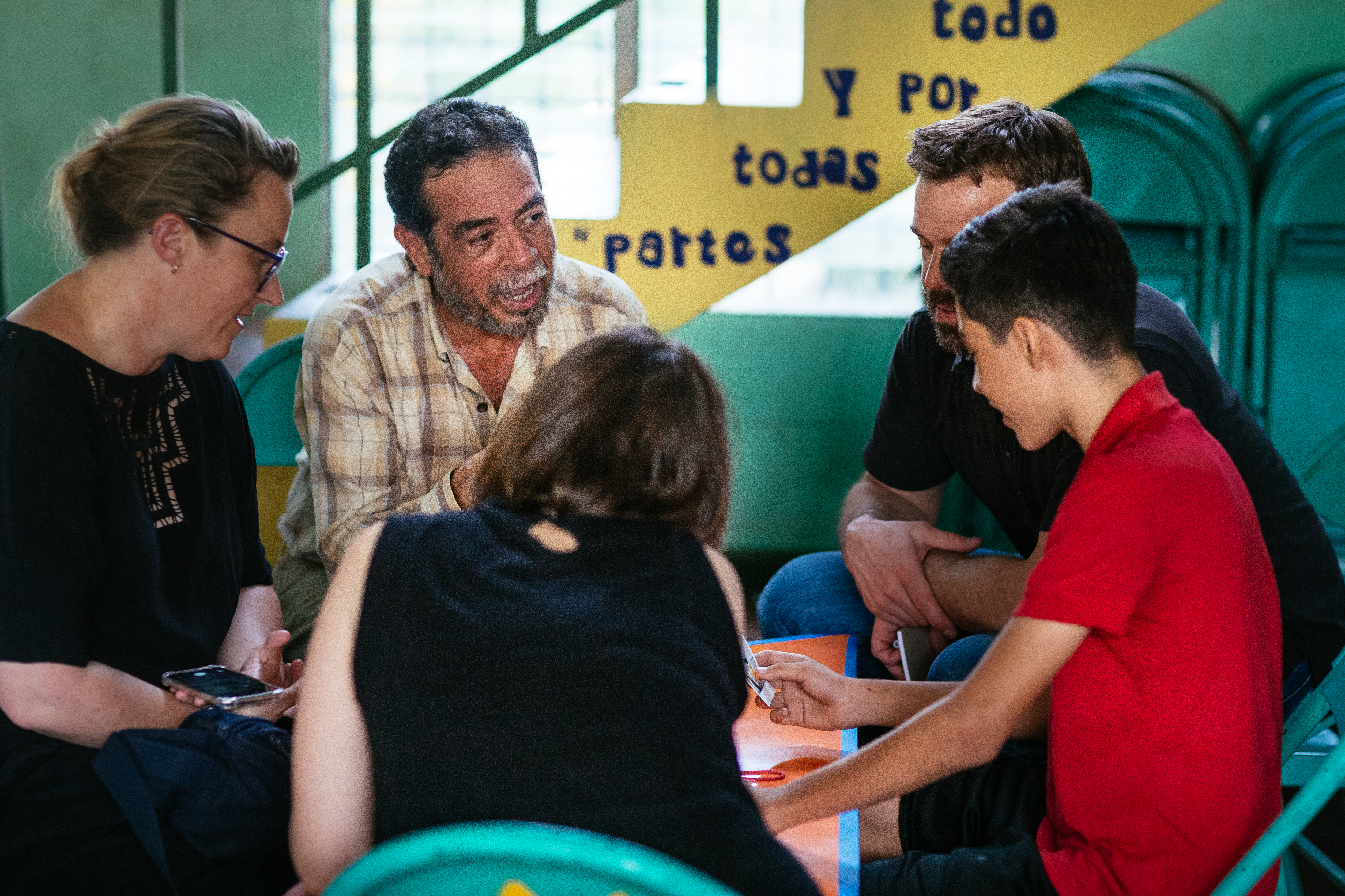 Drawn team listening closely to an older local man during a Color Movement session in El Salvador
