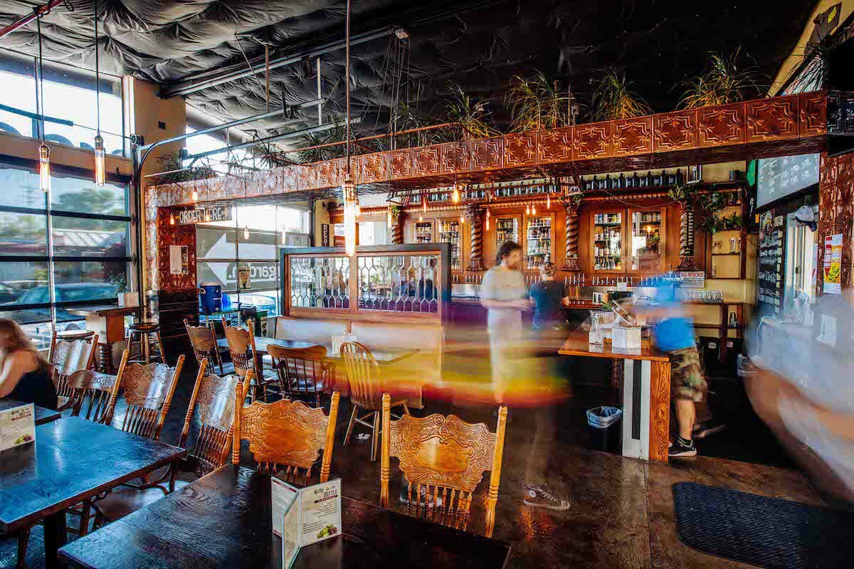 Lively Beergarden interior with carved wooden chairs, hanging plants and a long bar