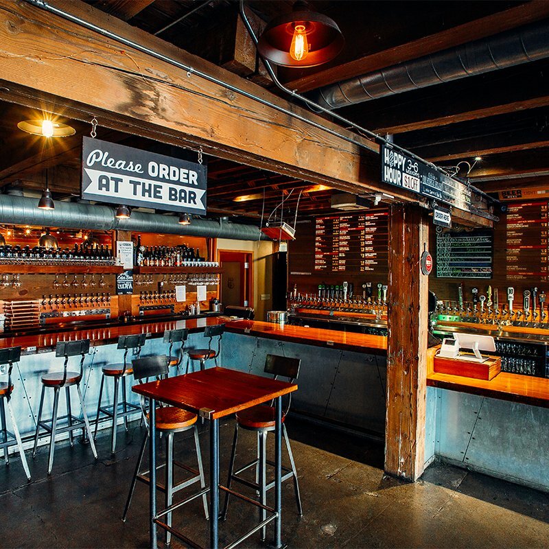 Tap and Growler pub interior with Please Order at the Bar sign, taps and high tables