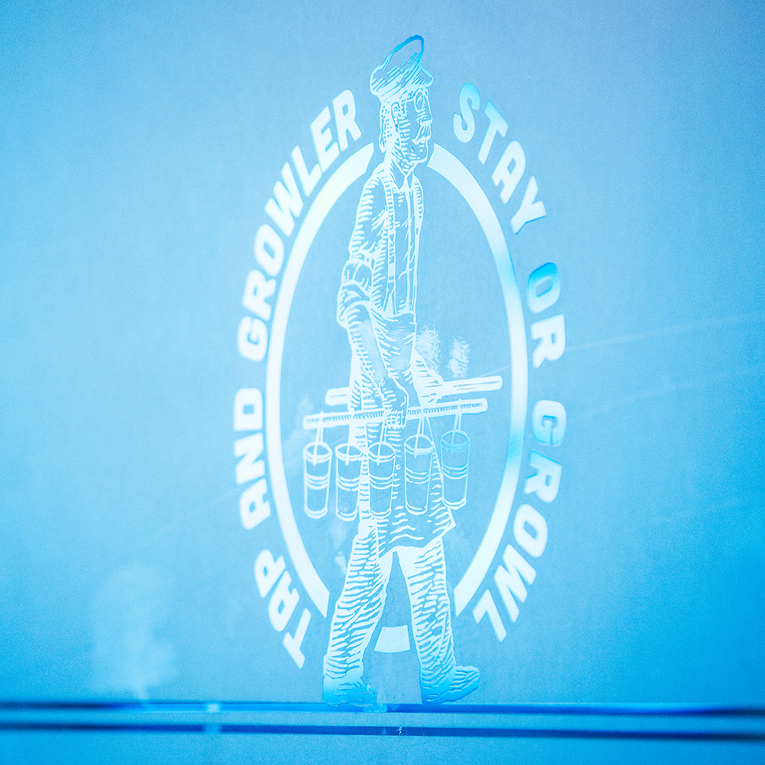 Etched glass Tap and Growler logo of a man carrying beer glasses, reading Stay or Growl