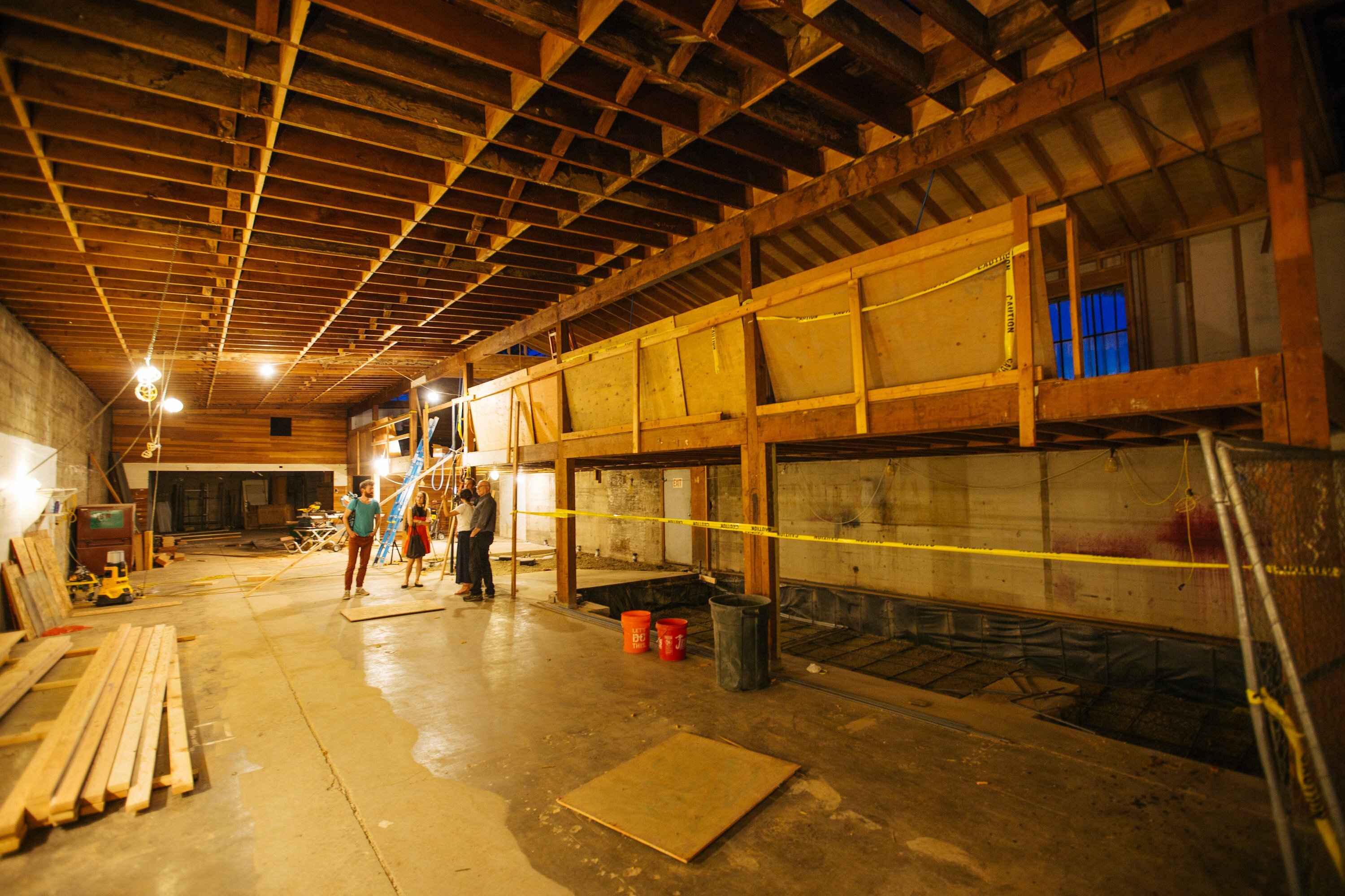 People standing in the unfinished Bard space mid-construction with exposed framing and caution tape