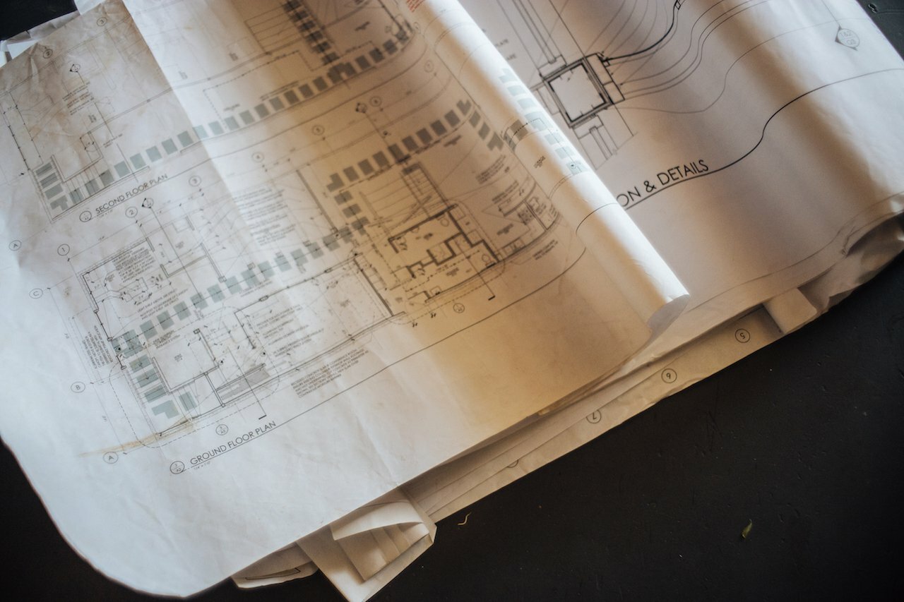 Rolled architectural blueprints labeled Ground Floor Plan and Details for Drawn's Bard HQ