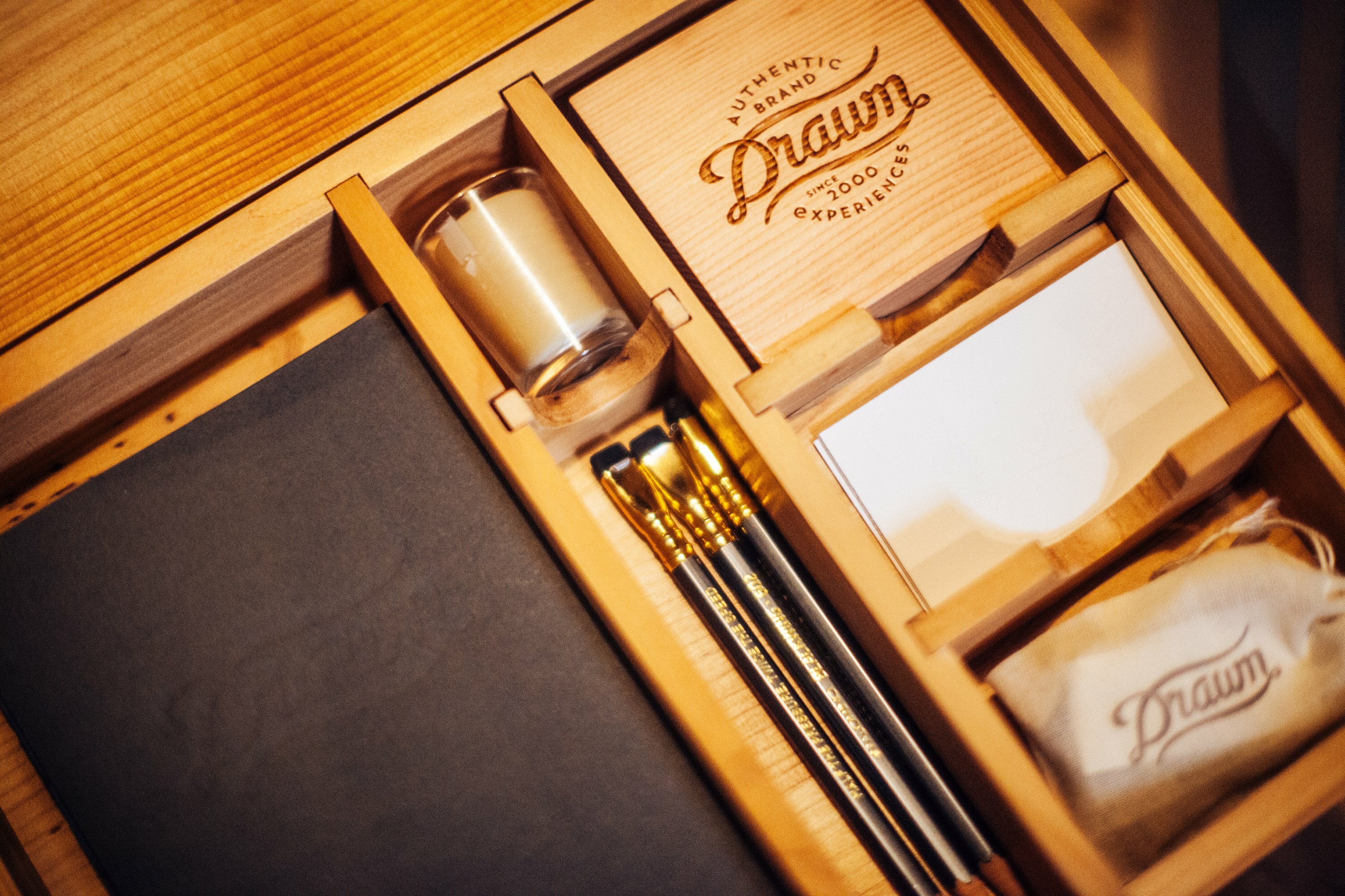 Drawn-branded wooden experience kit with candle, gold brushes and stamped Drawn soap bar