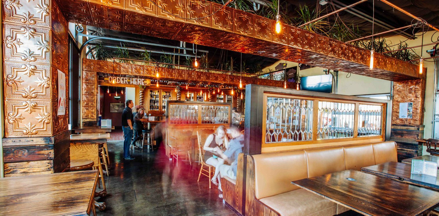 Drawn-designed pub interior with pressed-tin walls, Order Here sign and leather booths