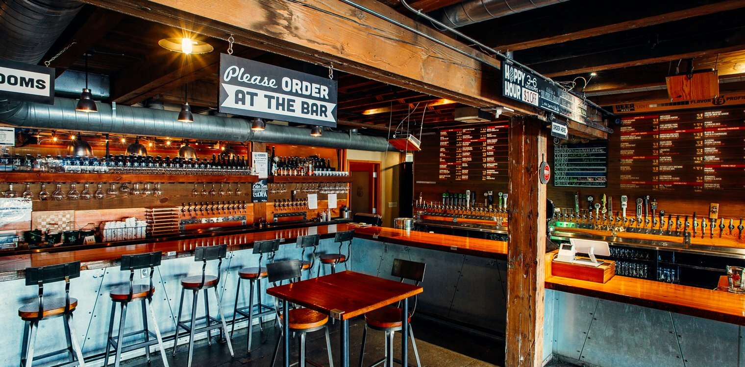 Dim Drawn-designed bar with 'Please Order at the Bar' sign, stools, beer taps and a chalkboard menu