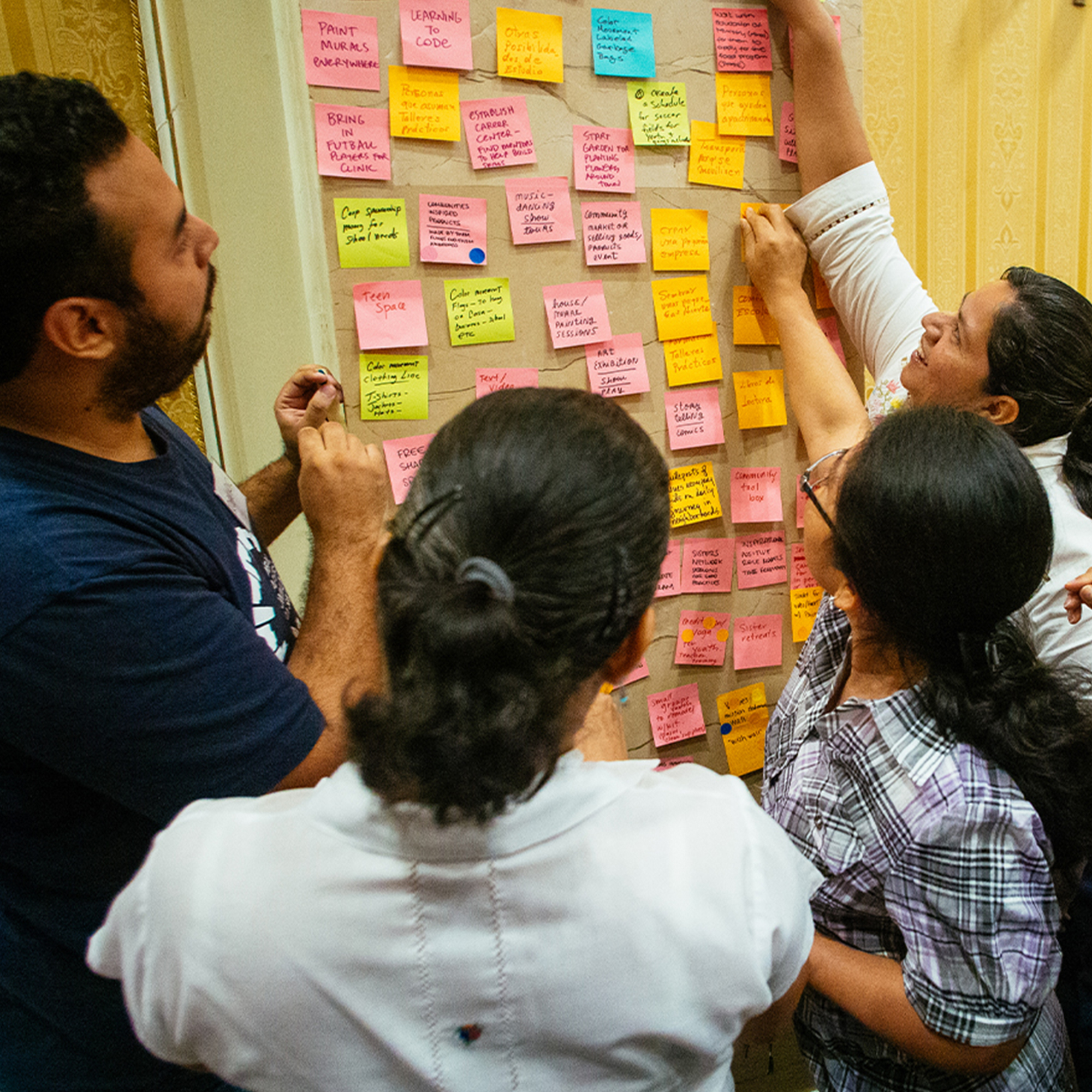 People clustering colorful sticky notes on a wall during a collaborative planning session