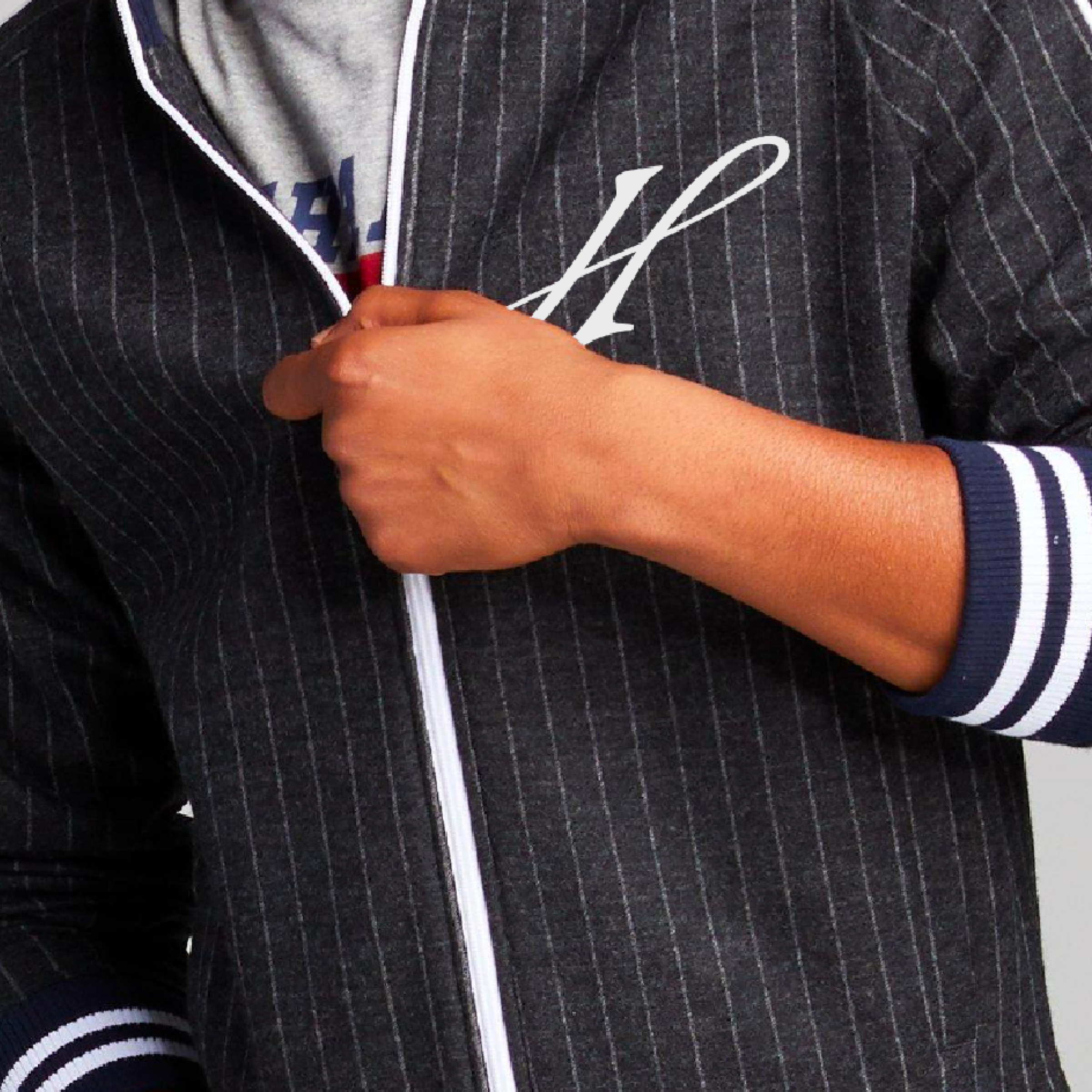 Close-up of person zipping a navy pinstripe Honeycomb jacket with script H monogram