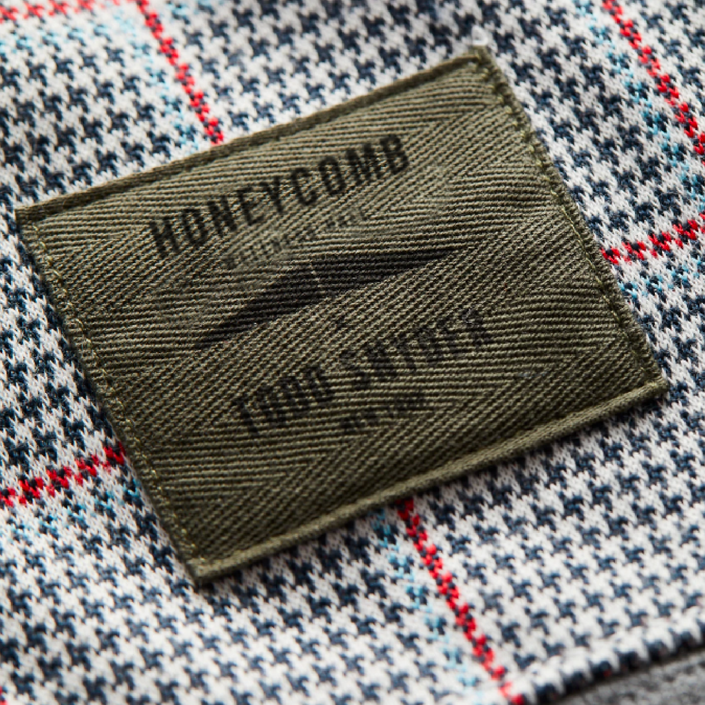 Olive woven Honeycomb Four Sports clothing label stitched on checked plaid fabric