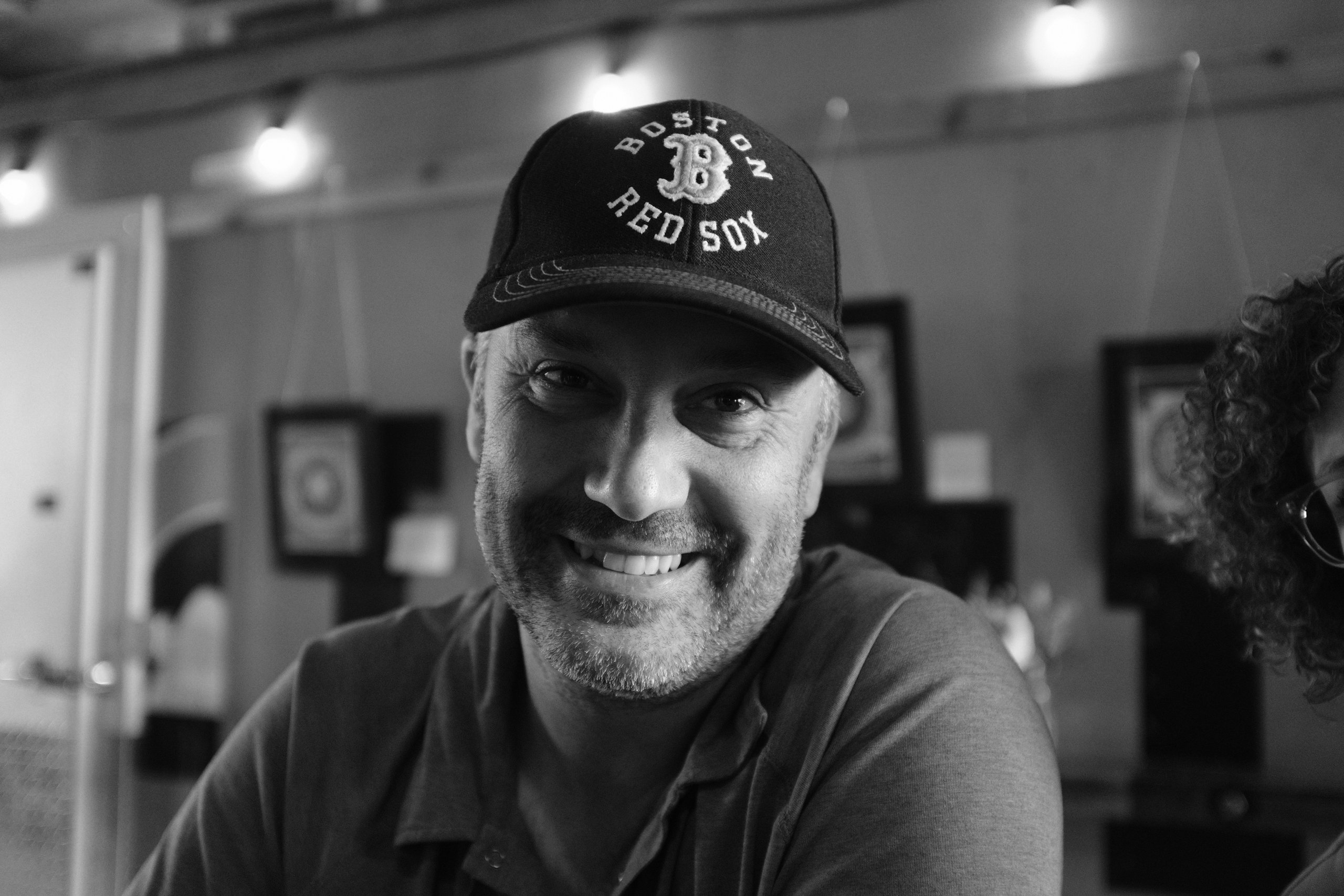 Black-and-white portrait of a smiling bearded man in a Boston Red Sox cap