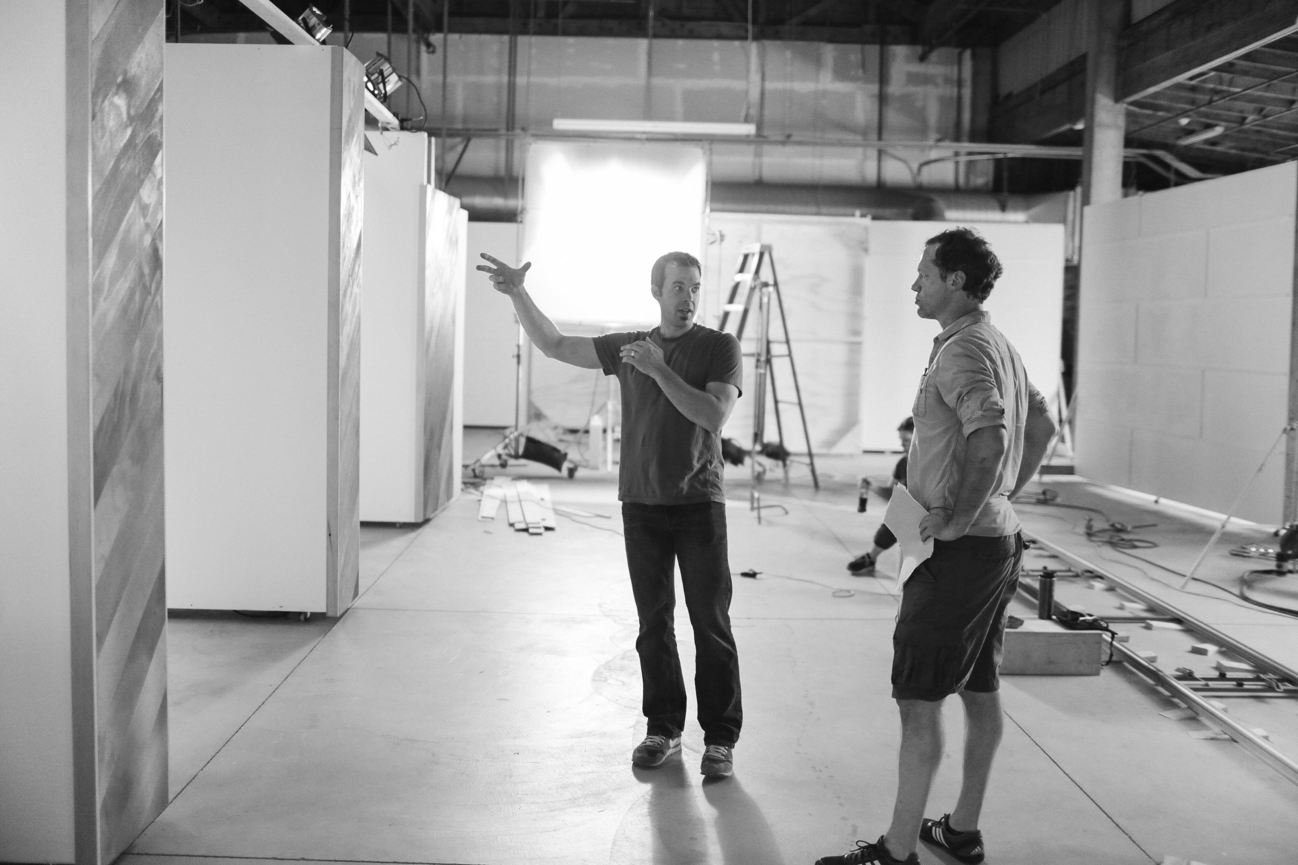 Two men talking on a photo studio set under construction, black and white