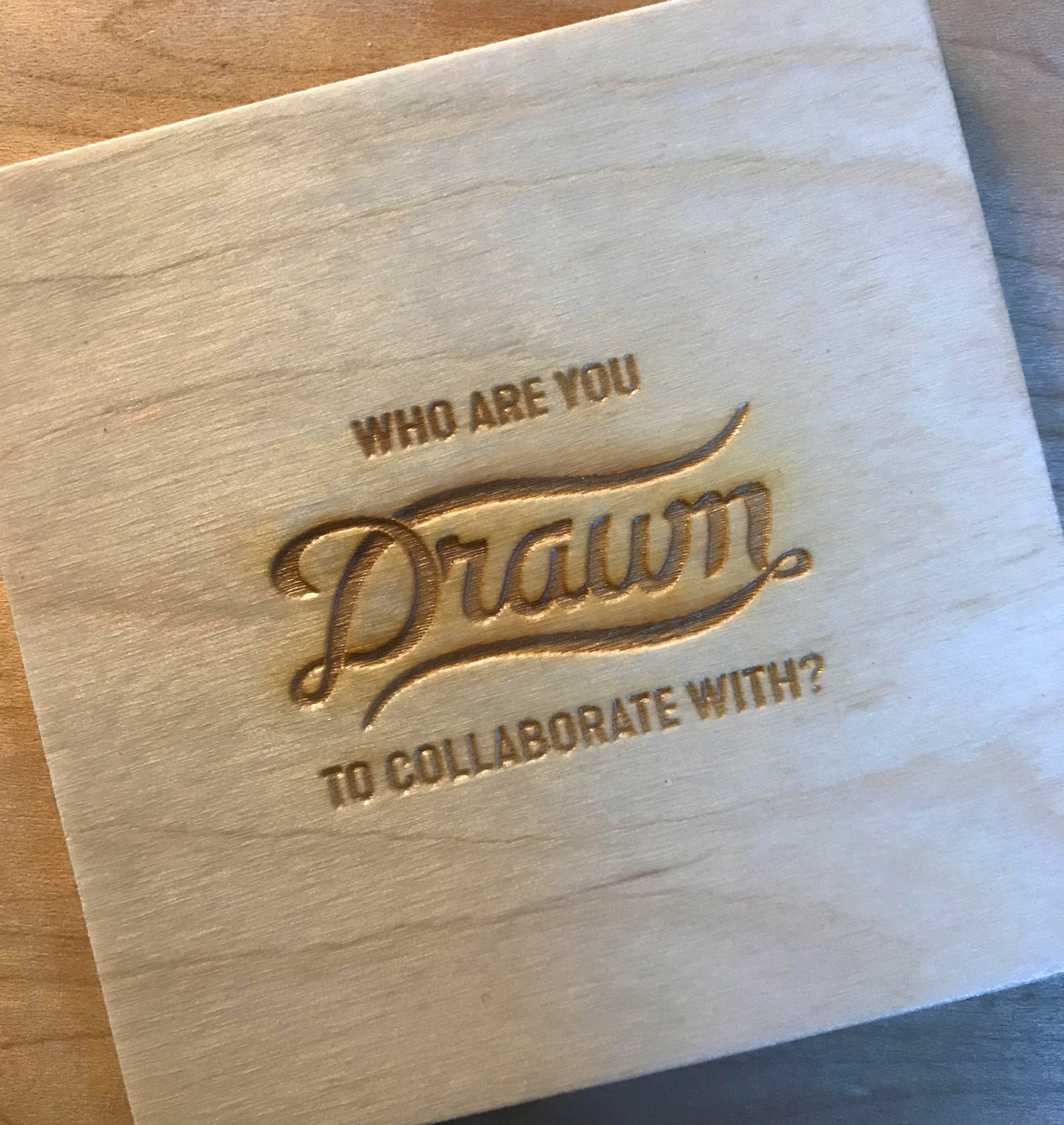 Wood coaster engraved 'Who are you Drawn to collaborate with?' with script logo