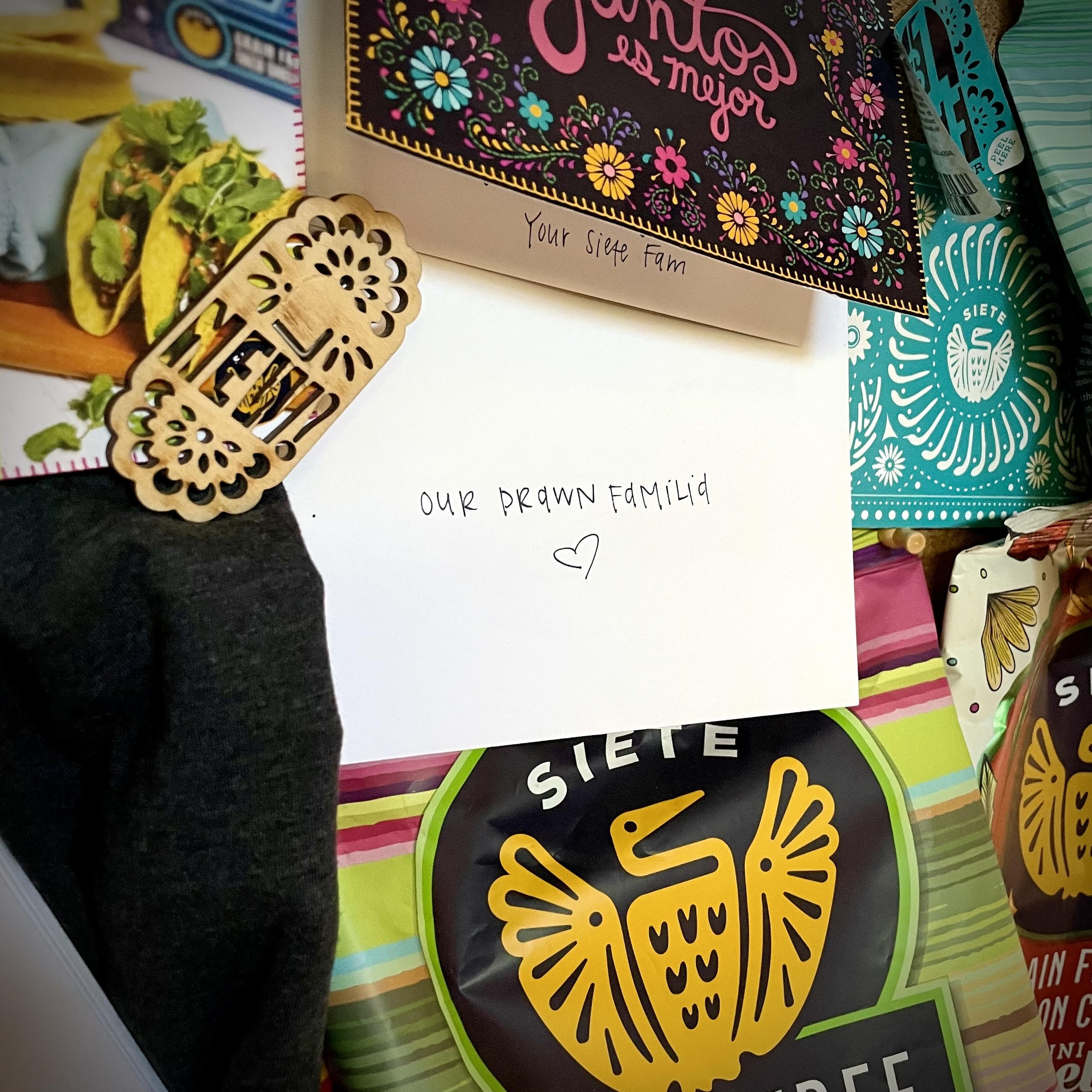 Siete gift package with a handwritten Our Drawn Familia card and chip bags