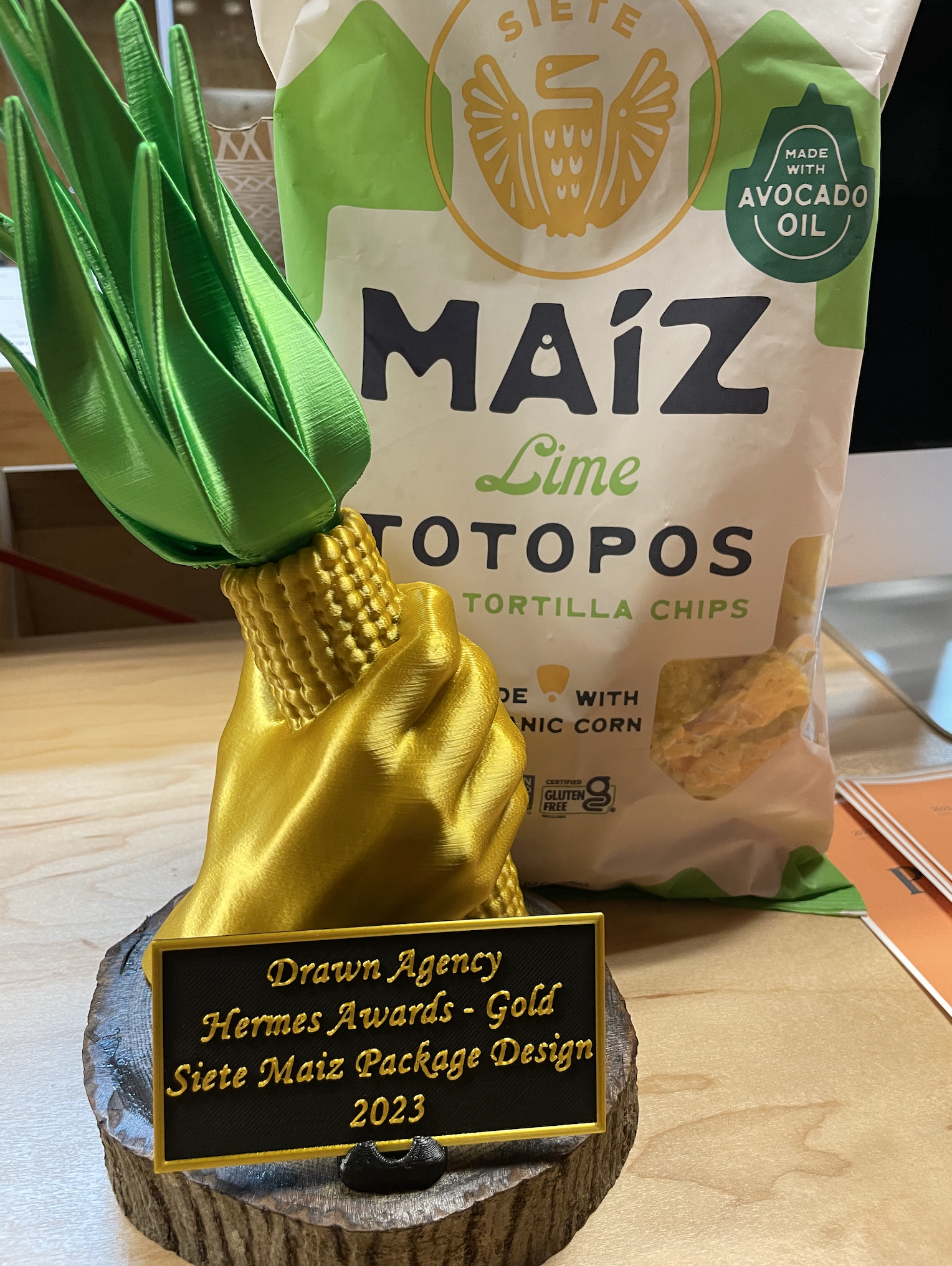 Gold corn Hermes Award trophy beside a Siete Maiz Lime Totopos chip bag