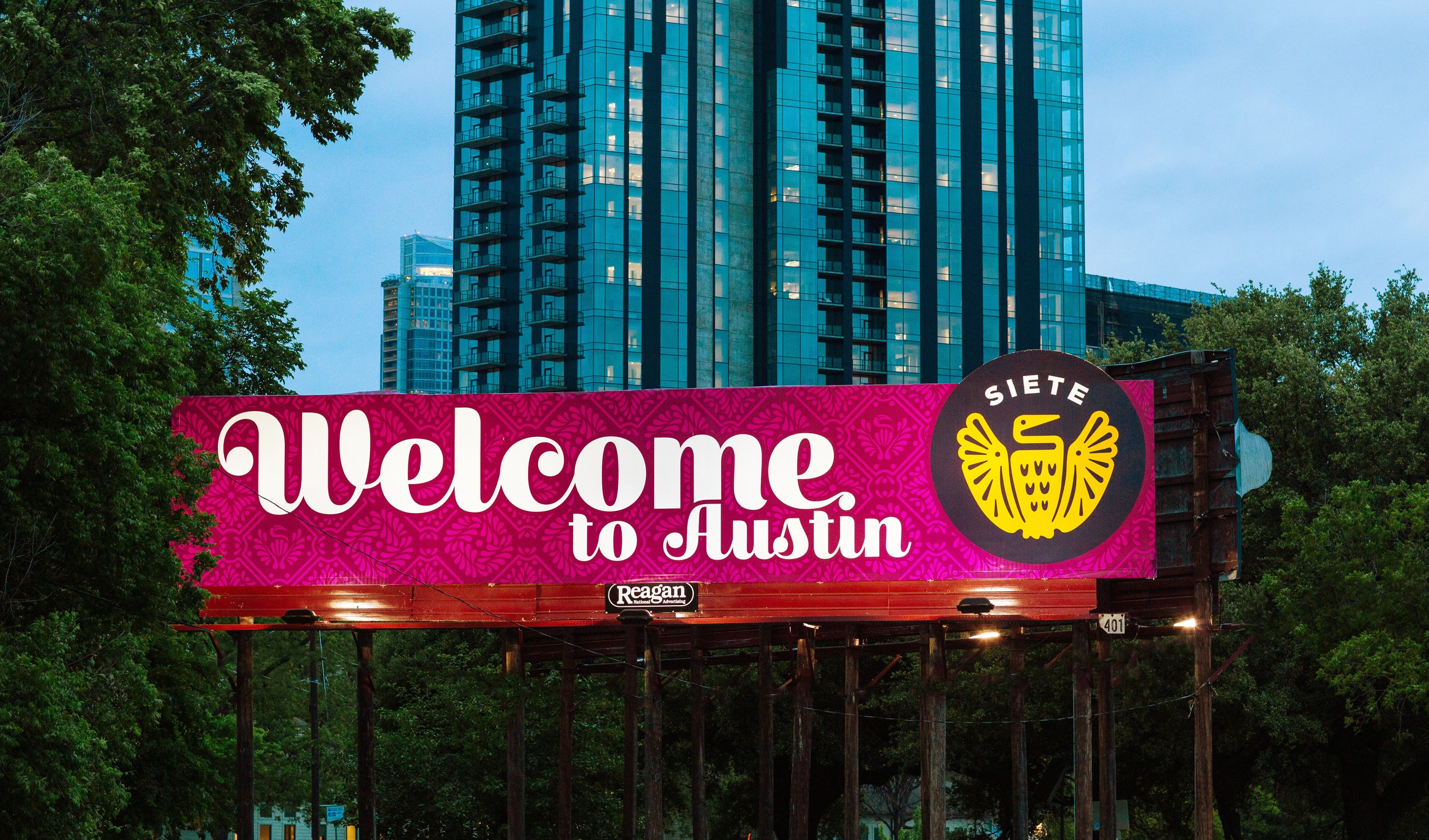 Pink Siete billboard reading Welcome to Austin in front of a city high-rise