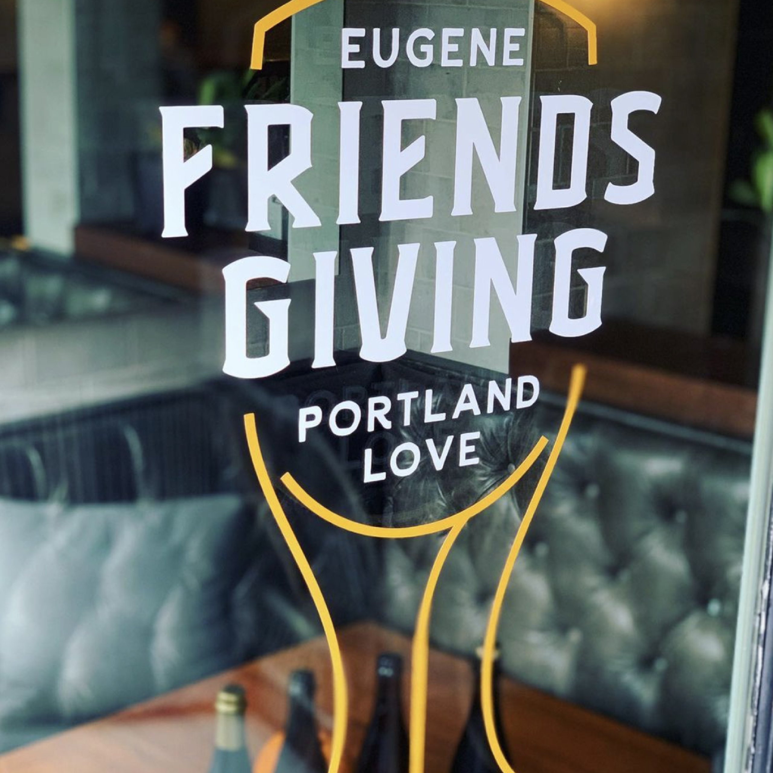 Window decal reading Eugene Friendsgiving Portland Love over a restaurant interior