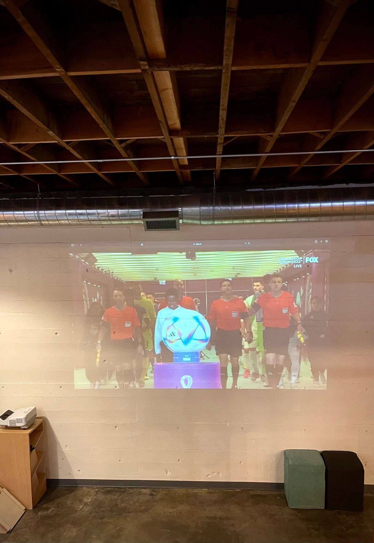 2022 FIFA World Cup broadcast projected on a brick wall, players and ball walking out