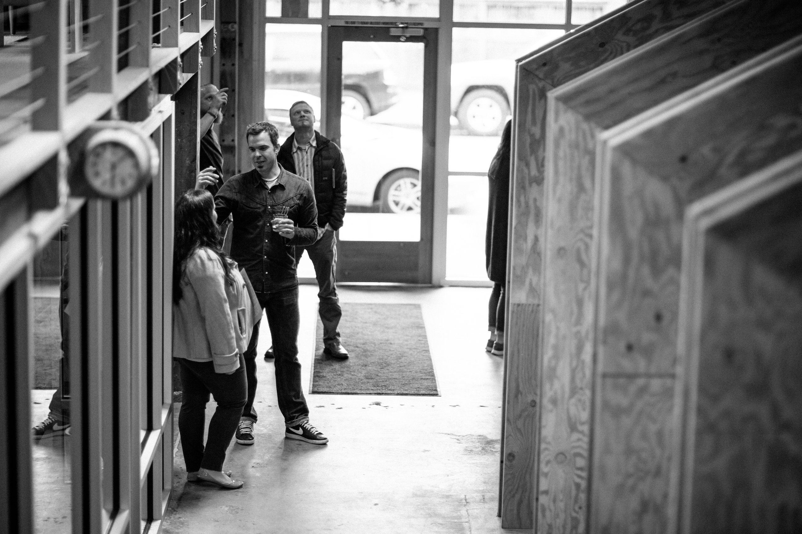 Black-and-white shot of people chatting near the entrance at Drawn's studio open house