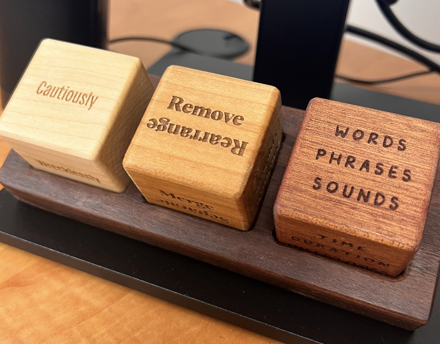 Three engraved wooden Unblocks cubes reading Cautiously, Remove, Words Phrases Sounds