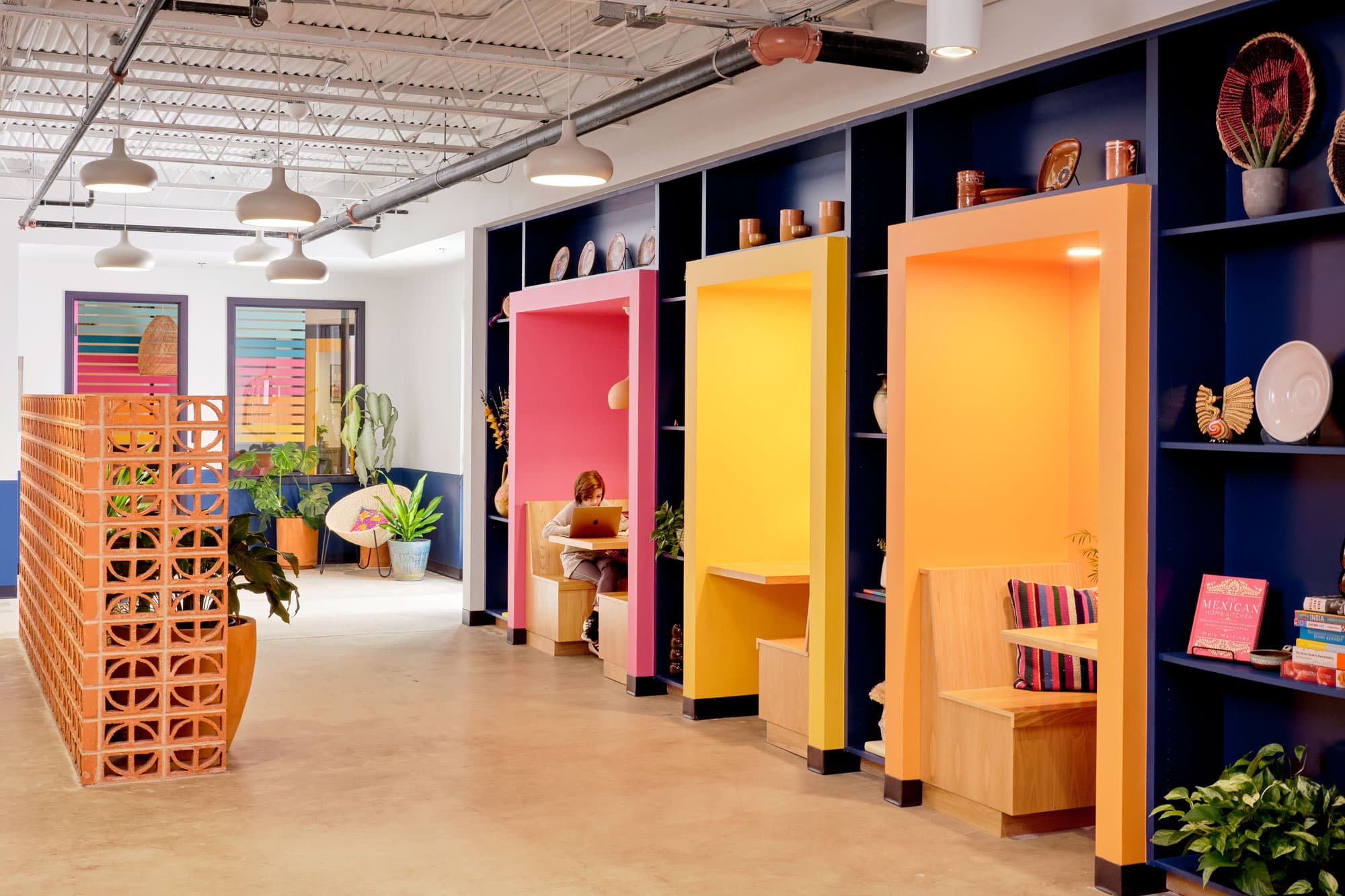 Colorful office with pink, yellow and orange study nooks and a person on a laptop