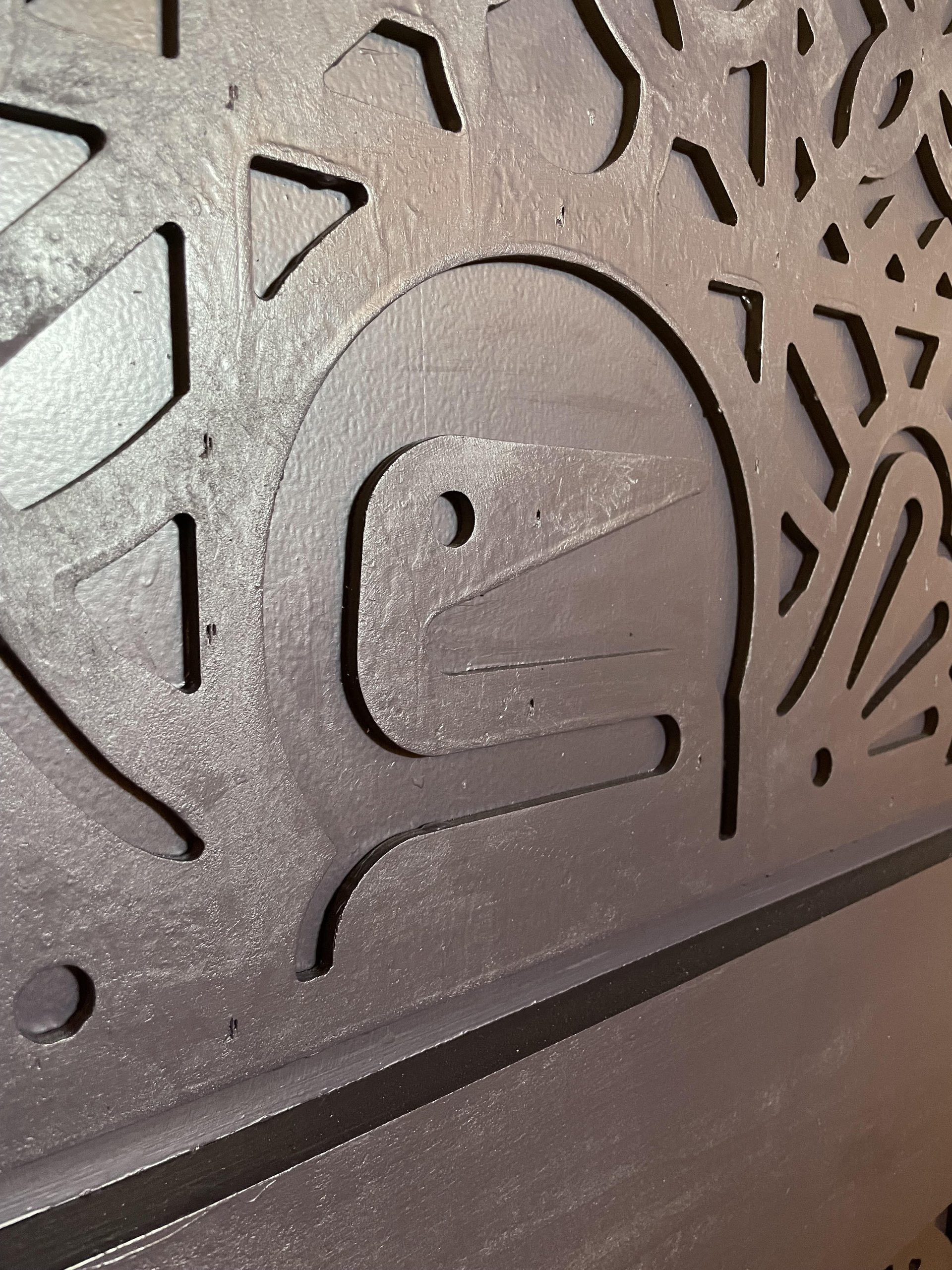 Close-up of a carved bird motif in a dark painted wooden decorative panel