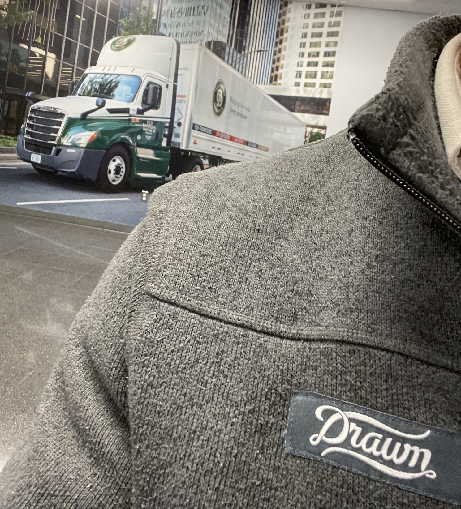 Close-up of a gray Drawn sweater with an Old Dominion freight truck behind