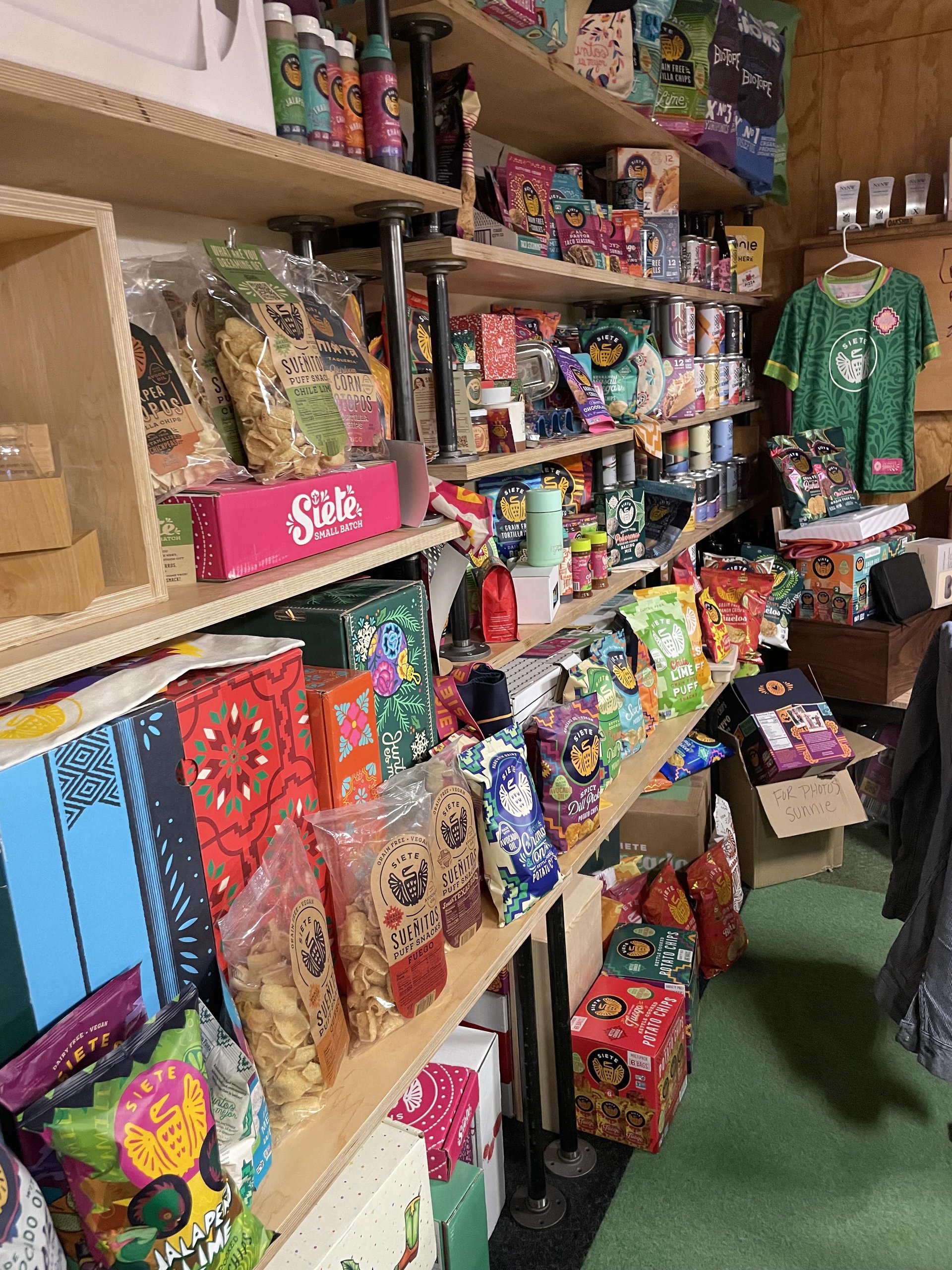 Shelves packed with colorful Siete snack products and a green Siete soccer jersey