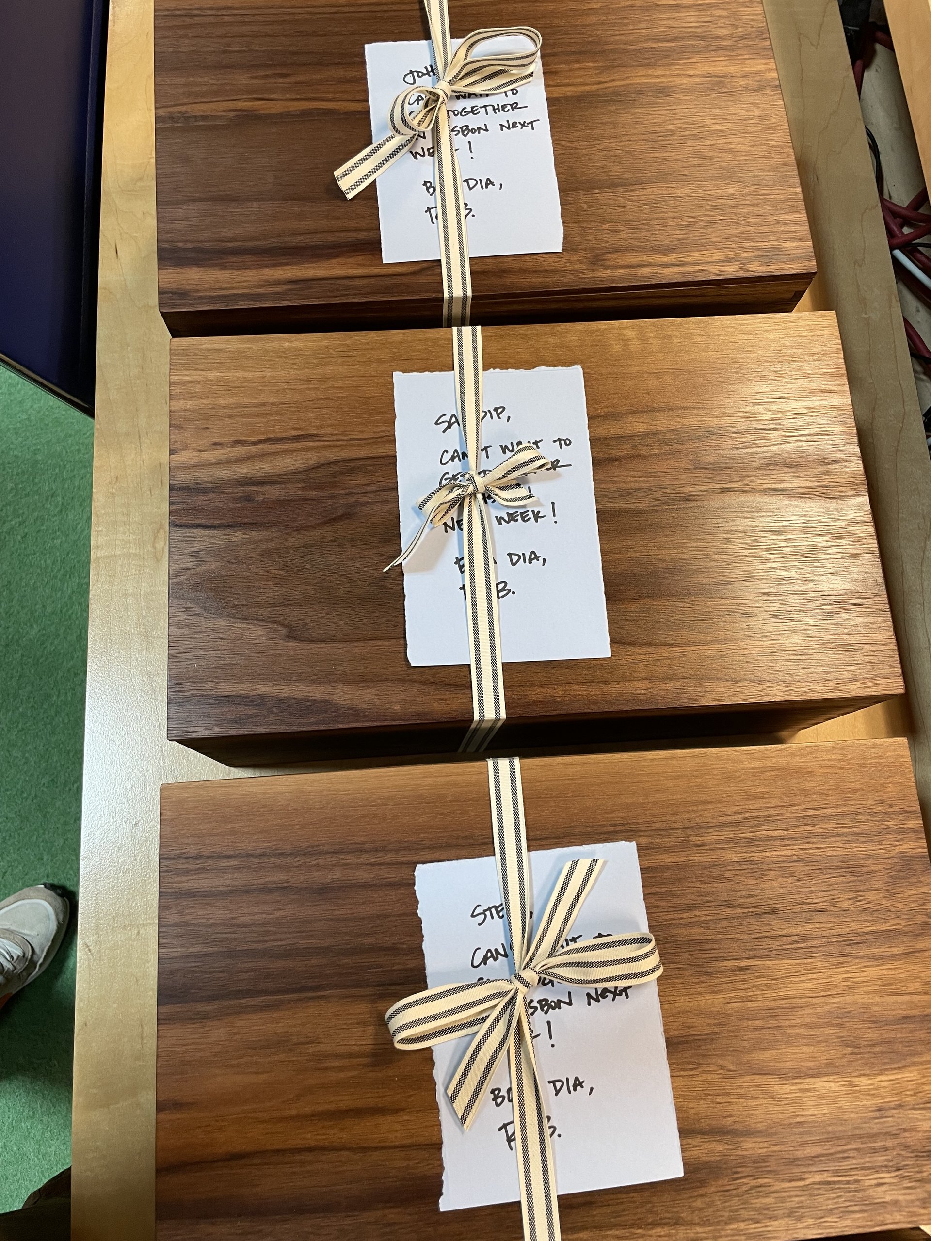 Three wooden gift boxes tied with striped ribbon and handwritten note cards