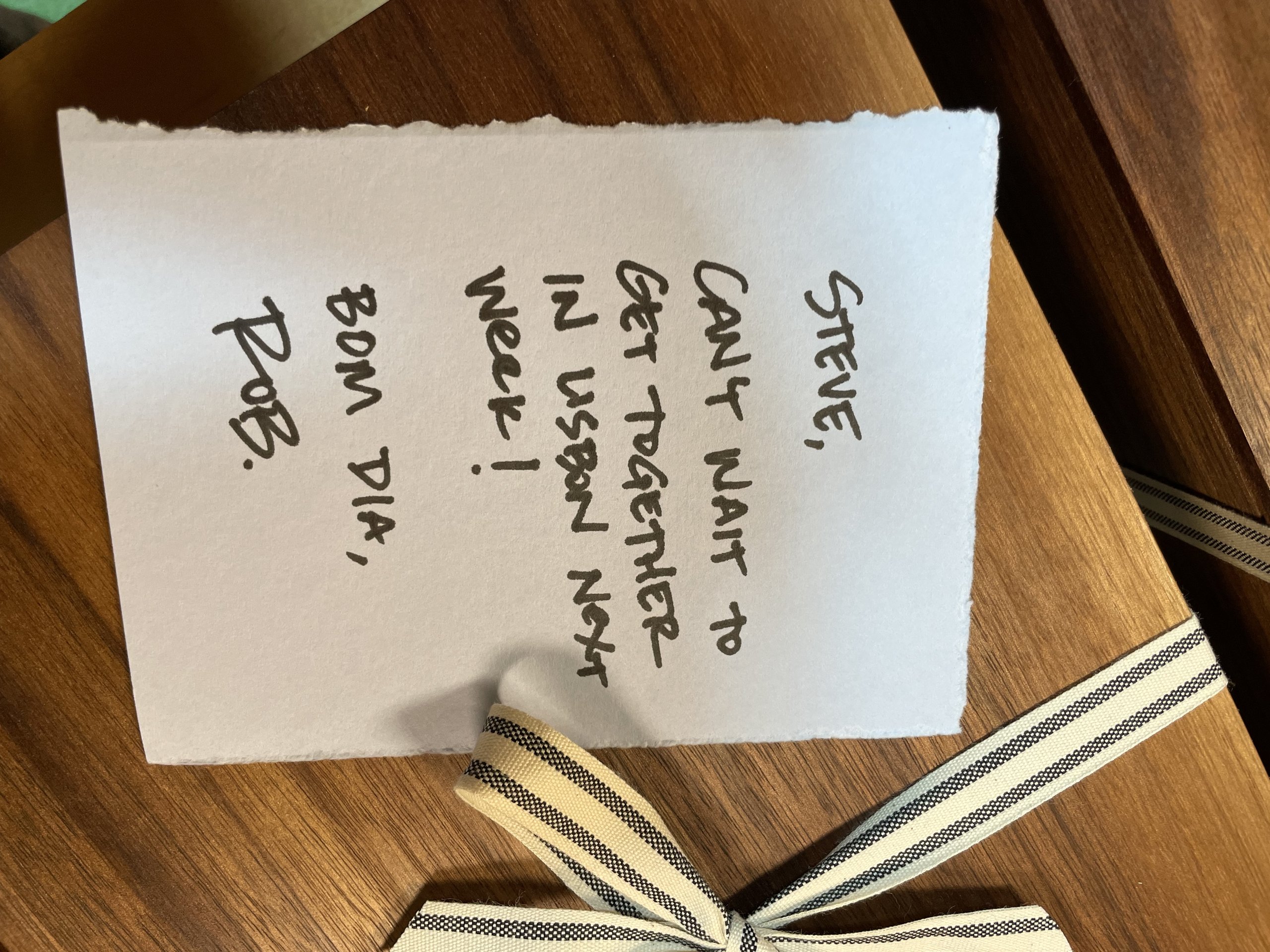 Handwritten note to Steve from Rob beside a striped ribbon bow on wood