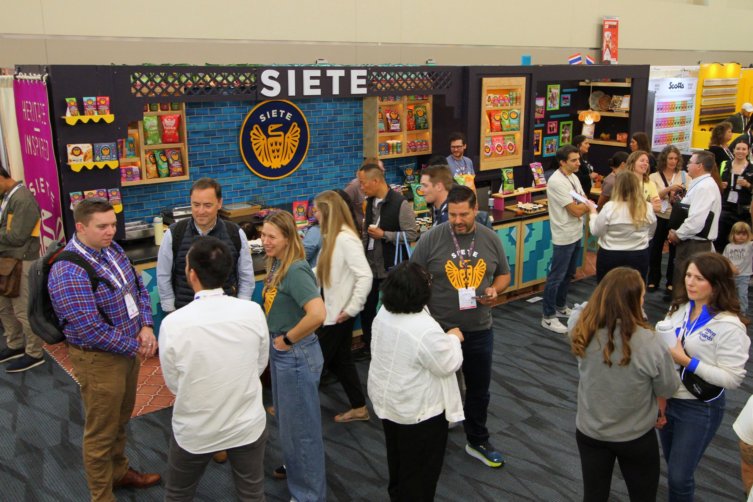 Crowd gathered at Siete trade show booth beneath gold eagle logo and blue tile