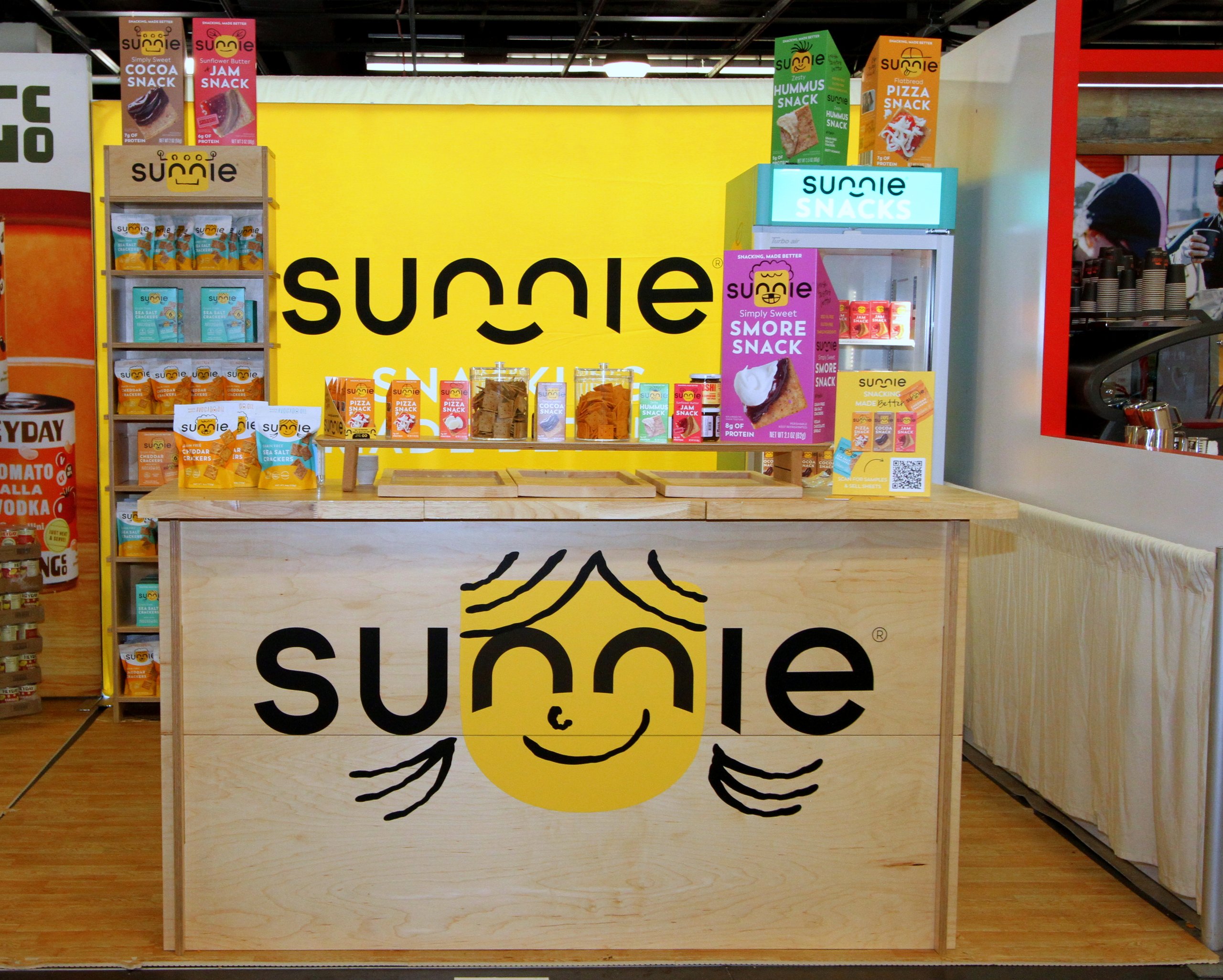 Sunnie snacks trade show booth with yellow branding and product displays