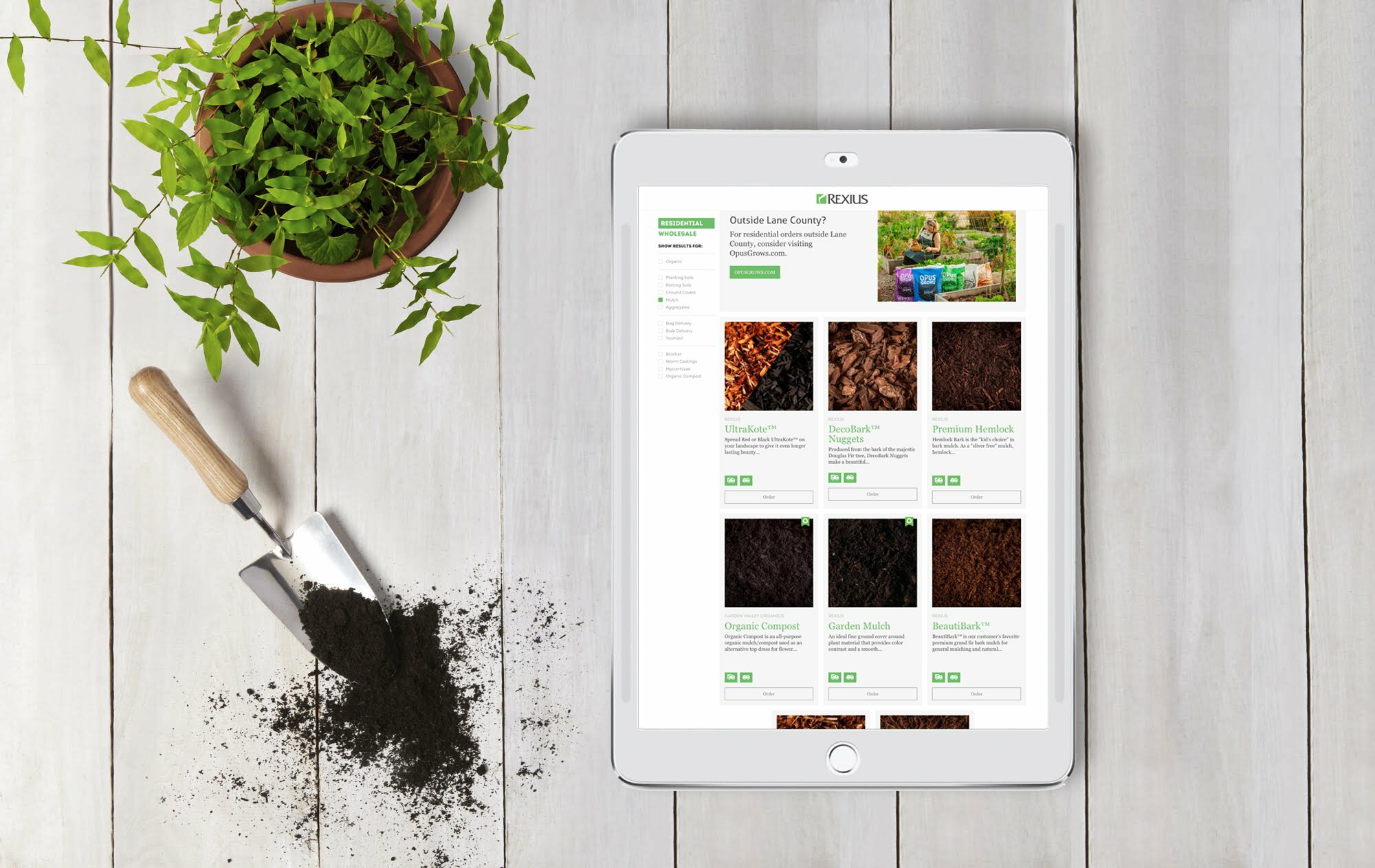 Tablet showing the Rexius product catalog beside a potted plant and garden trowel with spilled soil